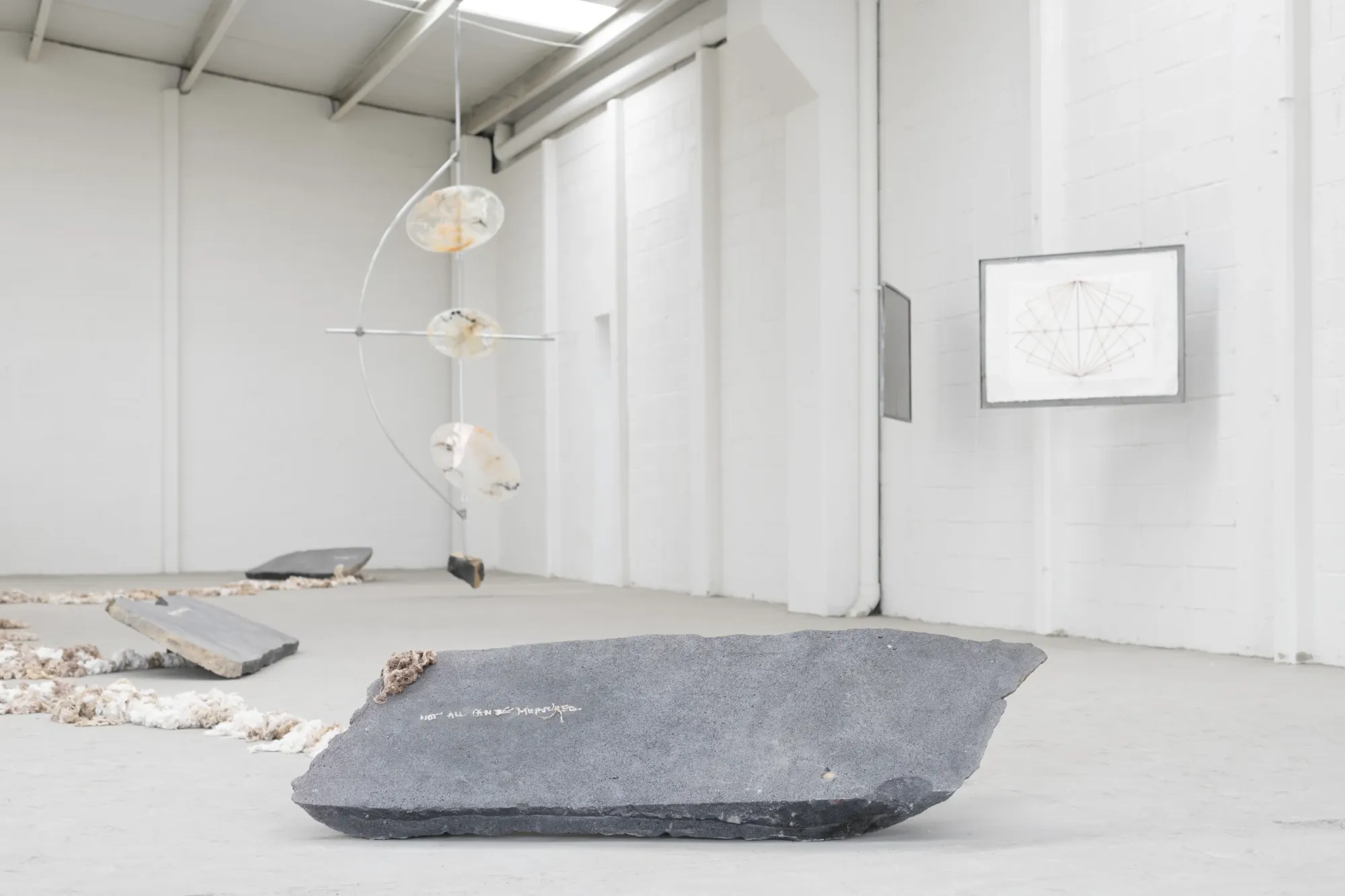 KiefferWoodtli, AXES, Alvarez Chida, Mexico City, 2026, volcanic stone slab with inscribed text on concrete floor, Pendulum and drawing in background