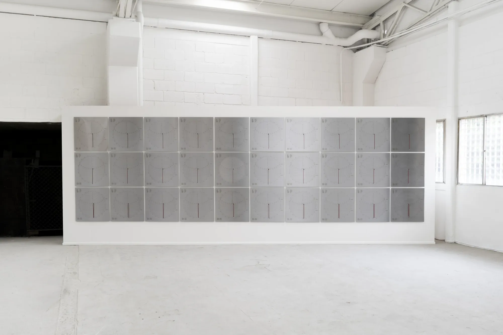 Kieffer Woodtli, heliosPlates, AXES, Alvarez Chida, Mexico City, 2026, grid of thirty grey solar chart panels with red gnomon on full wall