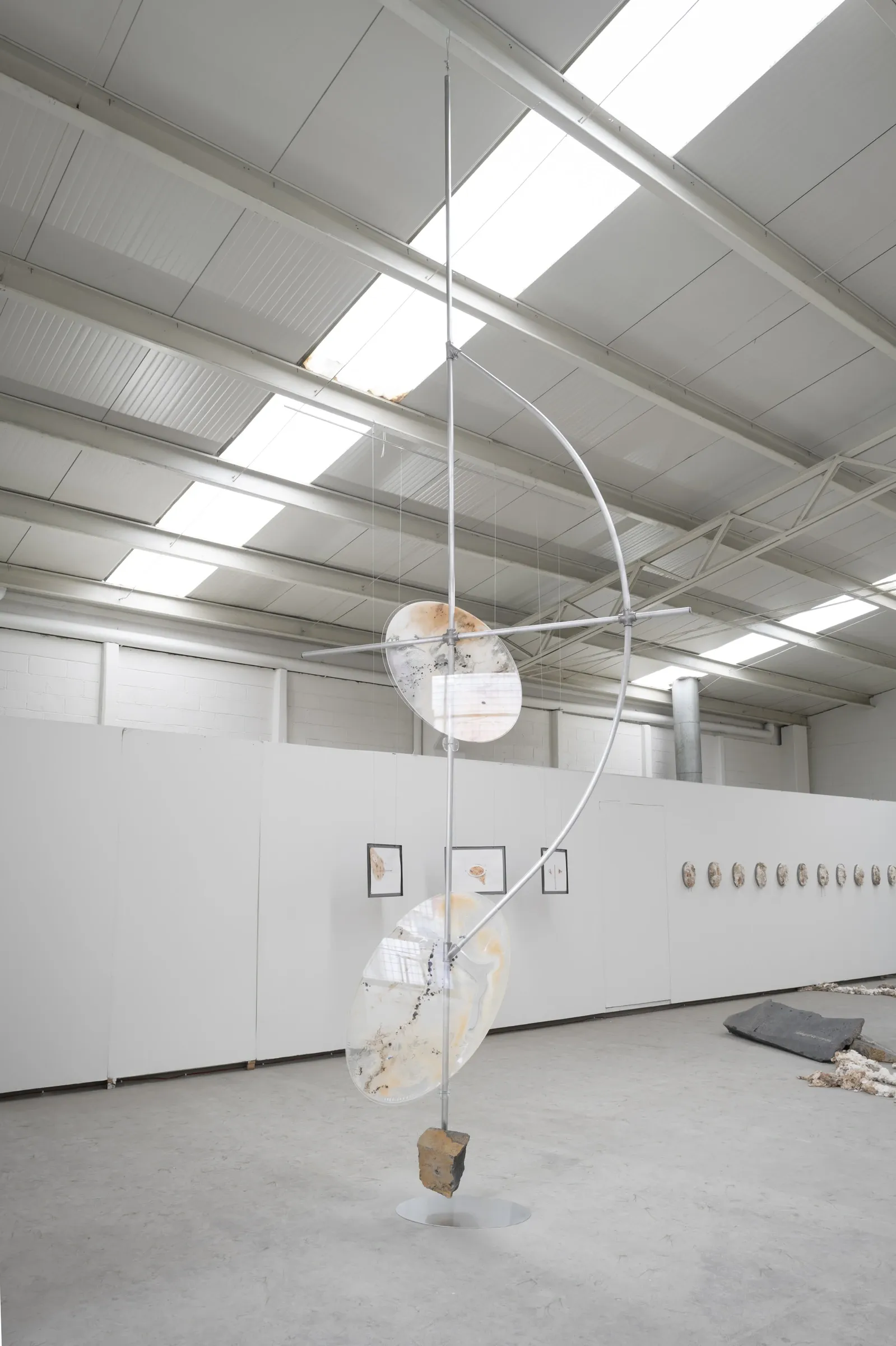 KiefferWoodtli, Pendulum, AXES, Alvarez Chida, Mexico City, 2026, pendulum sculpture with two discs and heliosPlates wall in background