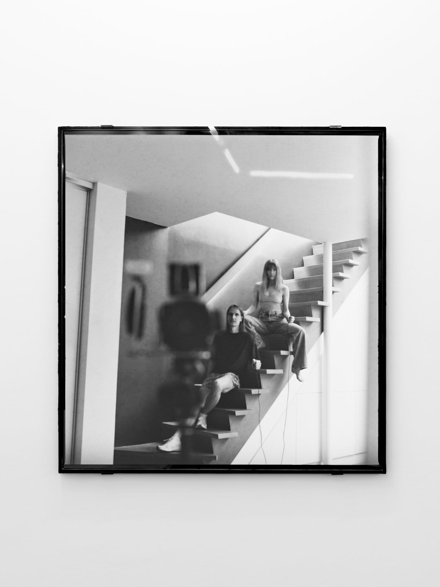 lom-of-LaMa, framed black-and-white photograph of two people seated on stairs, made with dual-shutter camera system requiring simultaneous activation, Call Me We, SUPERRAUM Dortmund, 2026