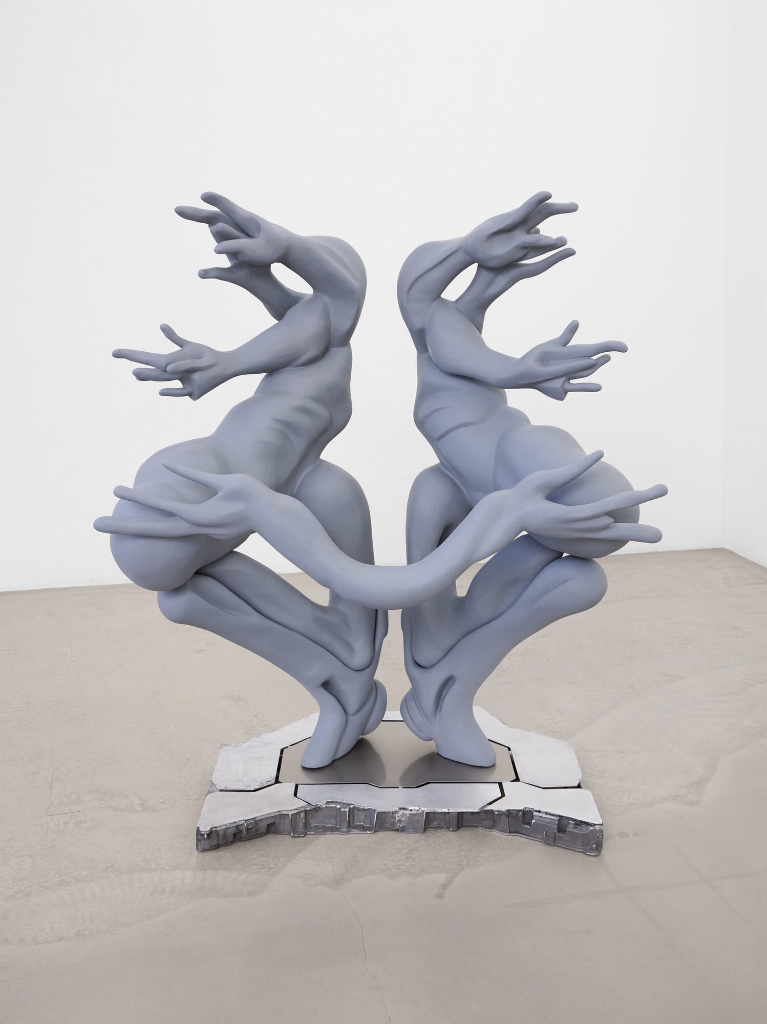 lom-of-LaMa, close-up of dual-body sculpture, two mirrored figures merging at the torso, 3D-printed in blue-grey, mounted on polished metal base, Call Me We, 2026