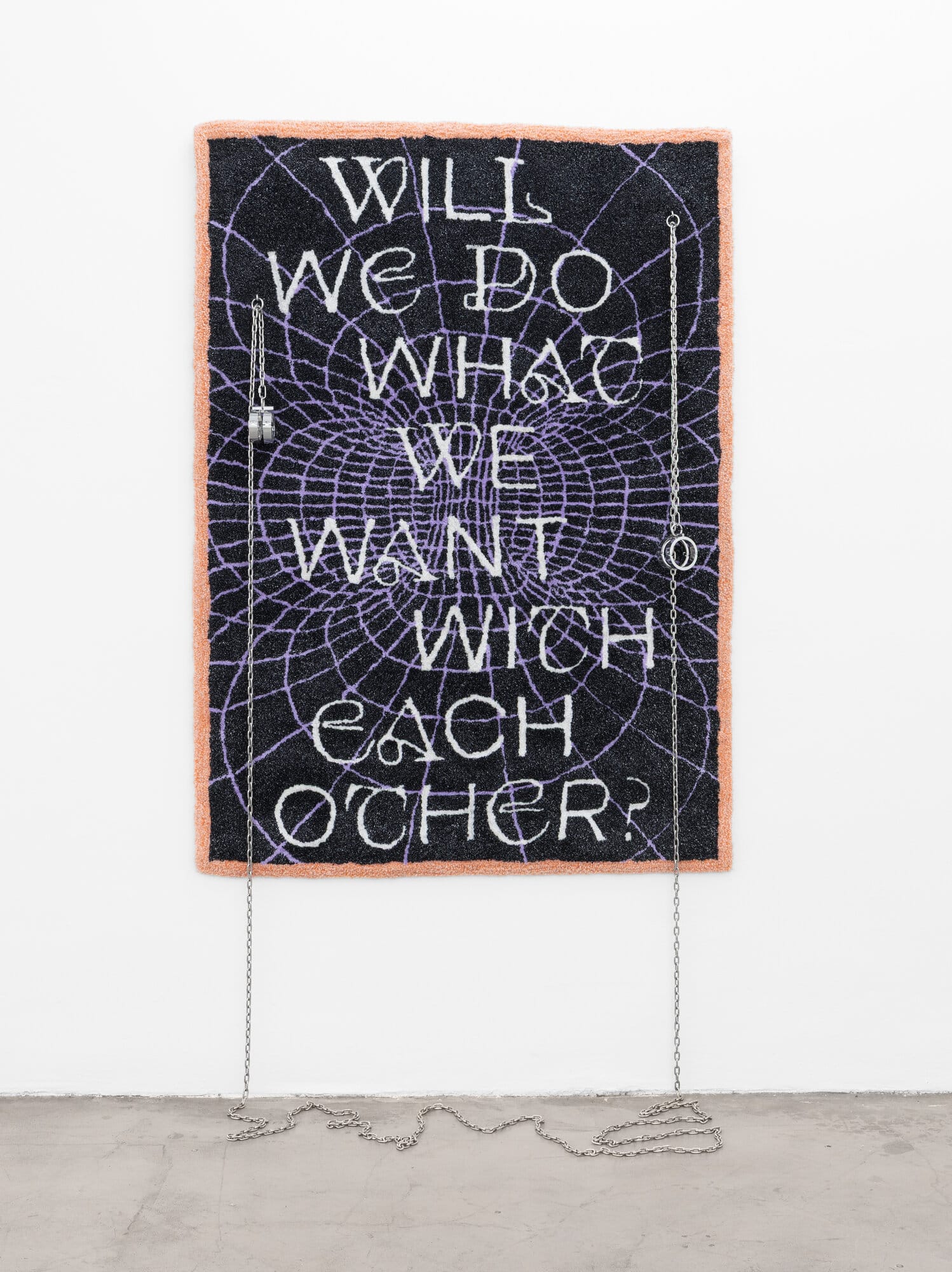 lom-of-LaMa, large textile work with text "Will We Do What We Want With Each Other?" in white lettering on black ground with spider-web pattern and orange border, metal chains hanging to floor, Call Me We, 2026