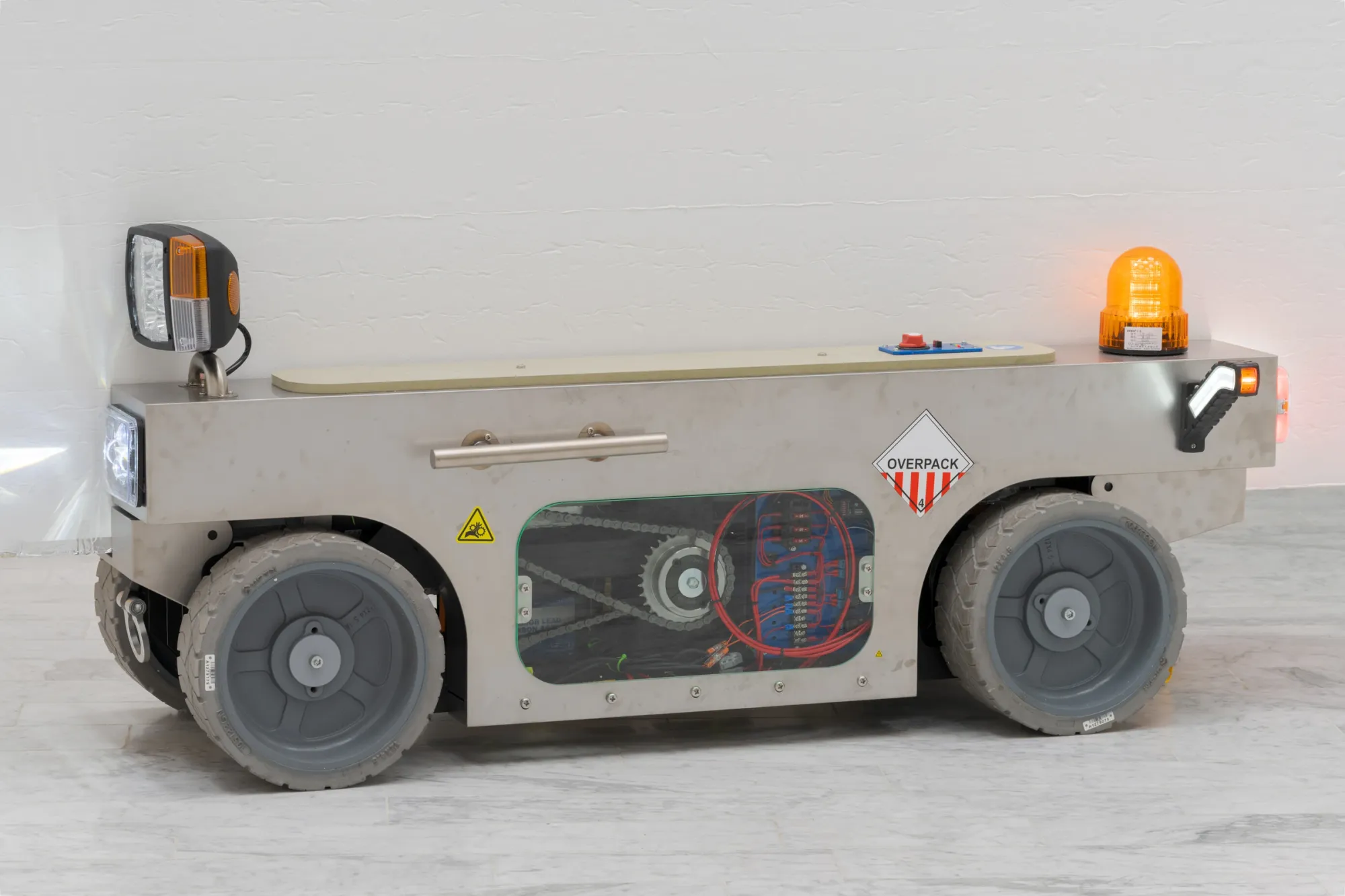Louis Morlæ, Walls at the World's End, Tranen, Hellerup, 2026, detail of robotic wall vehicle showing interior electronics, drive chain, and OVERPACK label