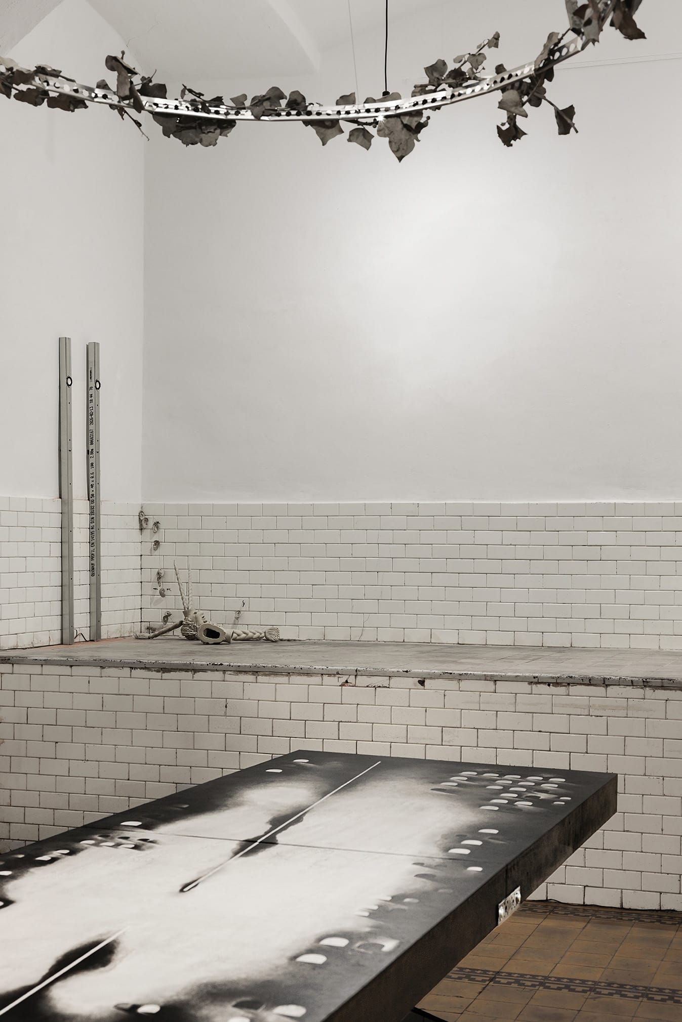 Palyvoda Struger Yesakova, Echoes that refuse to fade, FAVU Gallery Brno, 2026, wide room view with table surface skull imagery and hexagonal floor grid