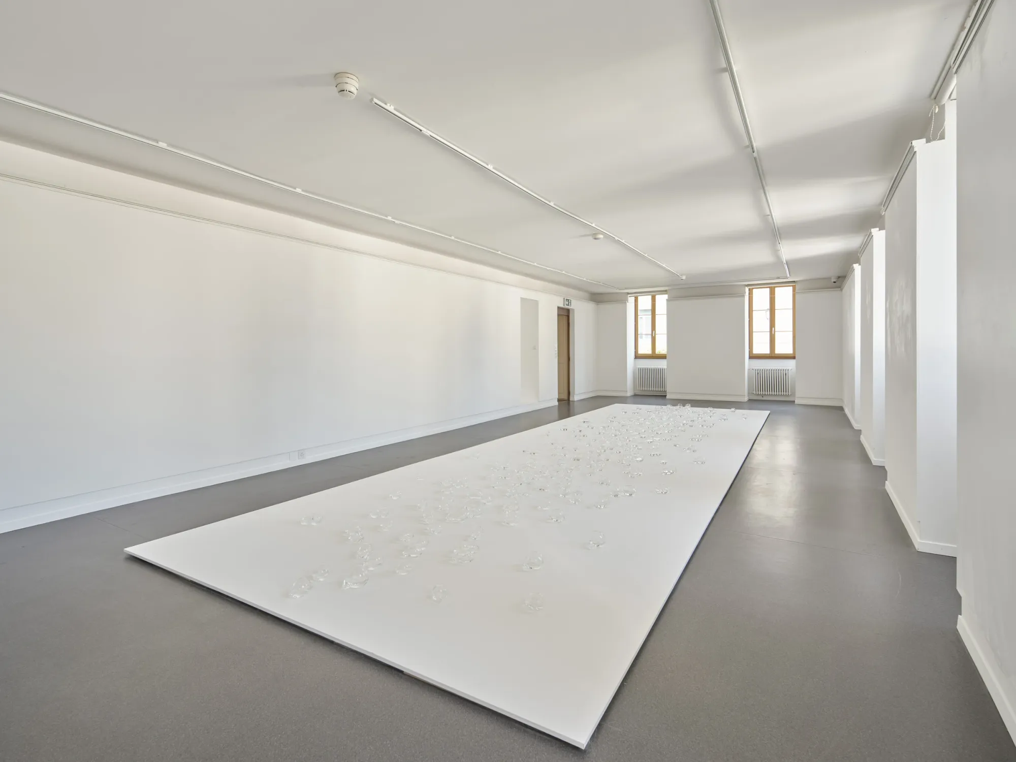 Rahel Oberhummer, Plaine Morte, 2025, wide room view, white rectangular field with glass bubbles scattered across surface, Maison Visinand, Montreux