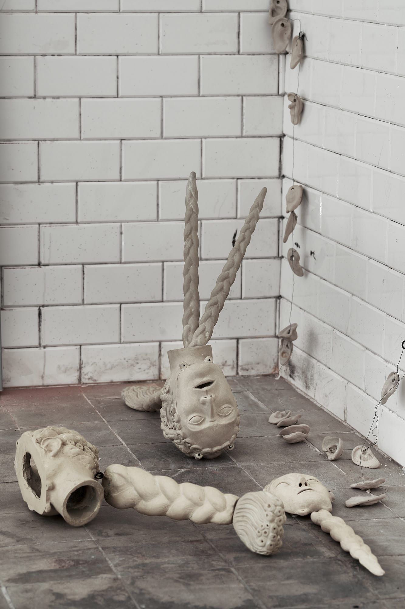 Céline Struger, Equalizer, Echoes that refuse to fade, FAVU Gallery Brno, 2026, ceramic heads on floor with braided and organic forms