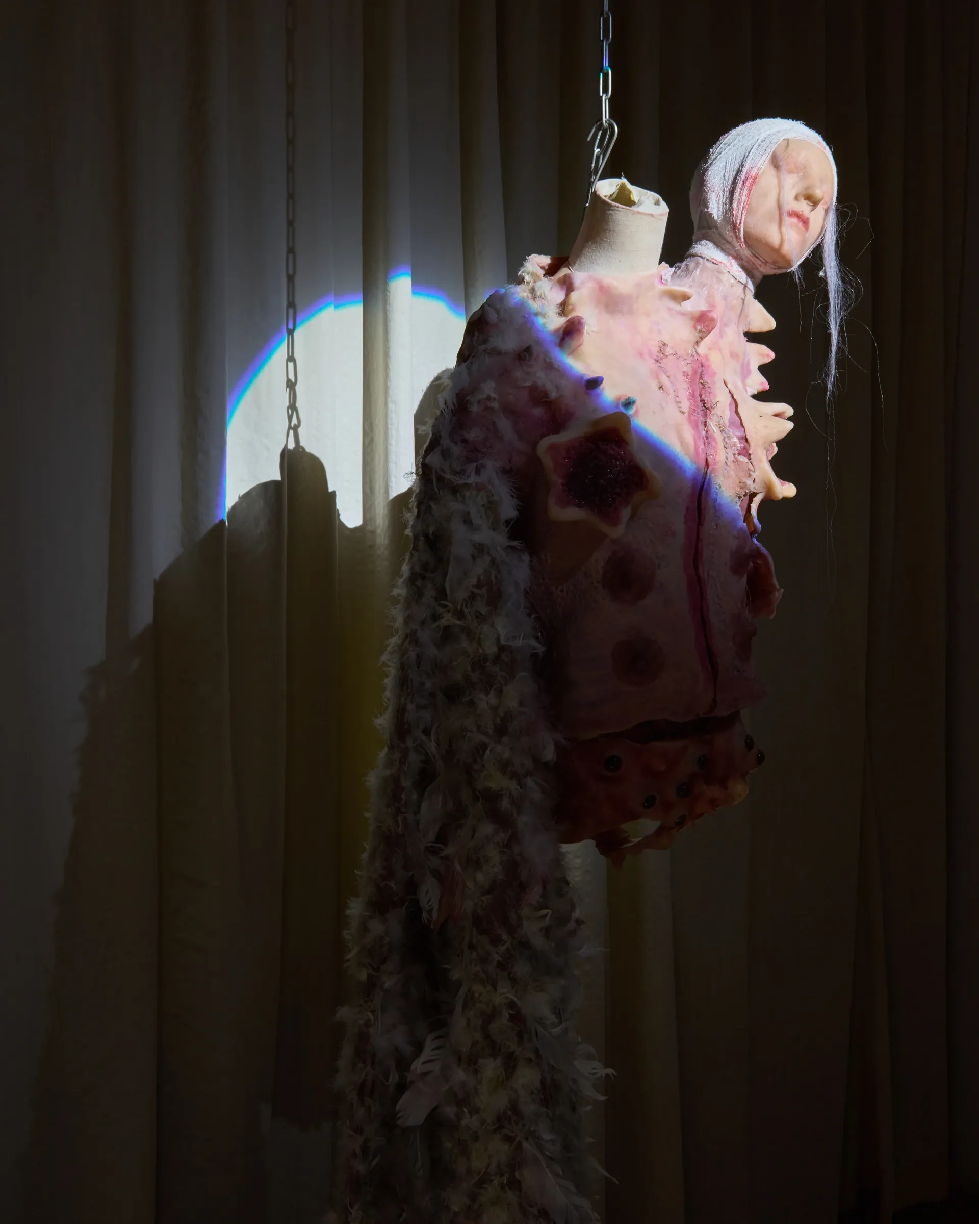 Tina Bxtq, Postangelic, Bleed Through, Galerie 35M2, Prague, 2026, detail of hanging costume with prismatic light effect on curtain