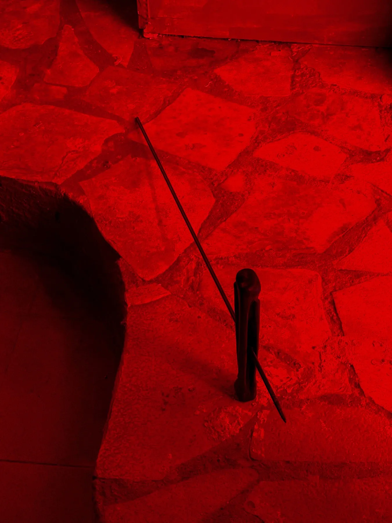 Sofiia Yesakova, Chapter II, Phantom Pförtnerhaus, Berlin, 2026, black wood form pierced by metal rod on red stone floor, overhead view