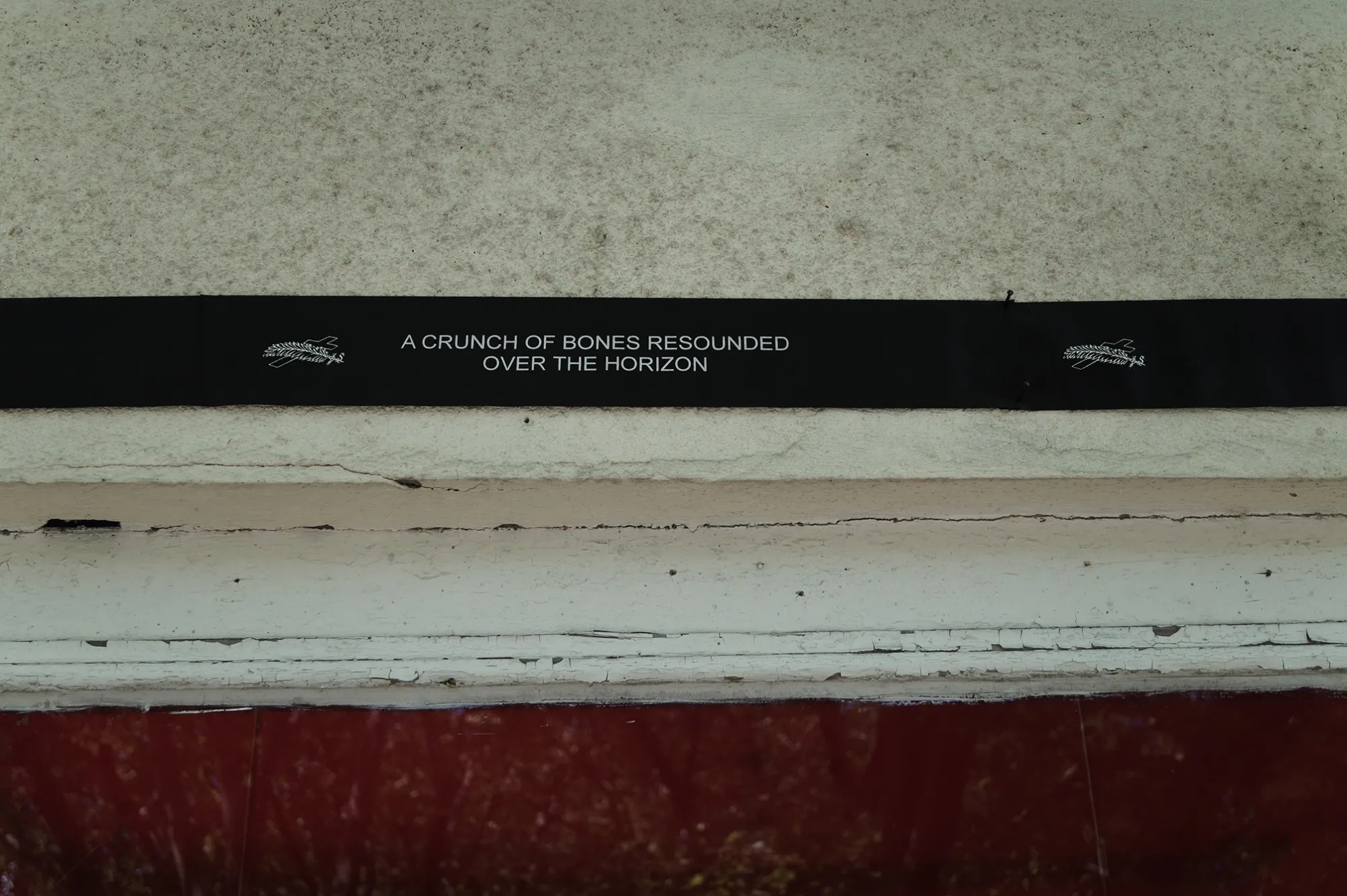 Sofiia Yesakova, A Crunch of Bones Resounded Over the Horizon, Phantom Pförtnerhaus, Berlin, 2026, black text band on window frame reading the work title