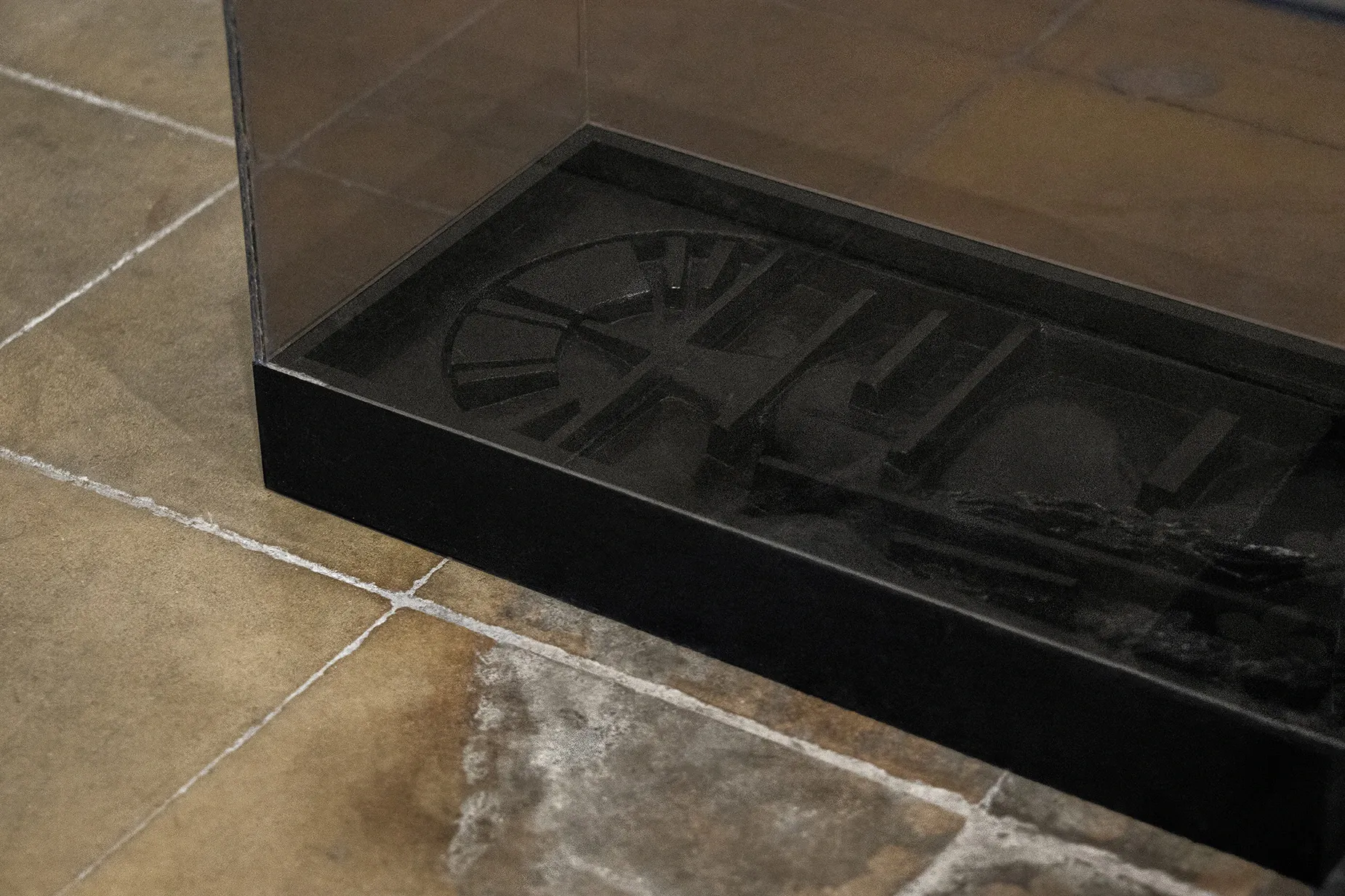 Sofiia Yesakova, Echoes that refuse to fade, FAVU Gallery Brno, 2026, table base detail with engraved architectural imagery under glass