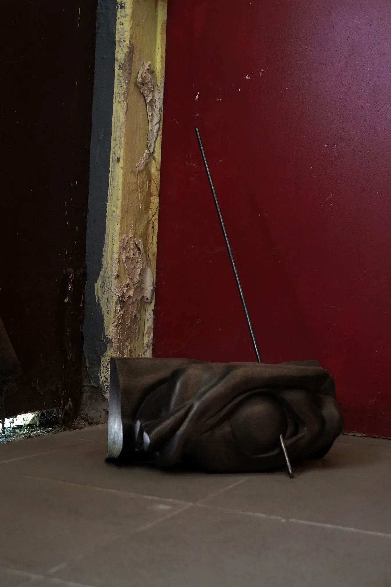 Sofiia Yesakova, Ugly Scenes. Nuances 3.1., Phantom Pförtnerhaus, Berlin, 2026, dark wood floor sculpture with metal rod at doorway threshold