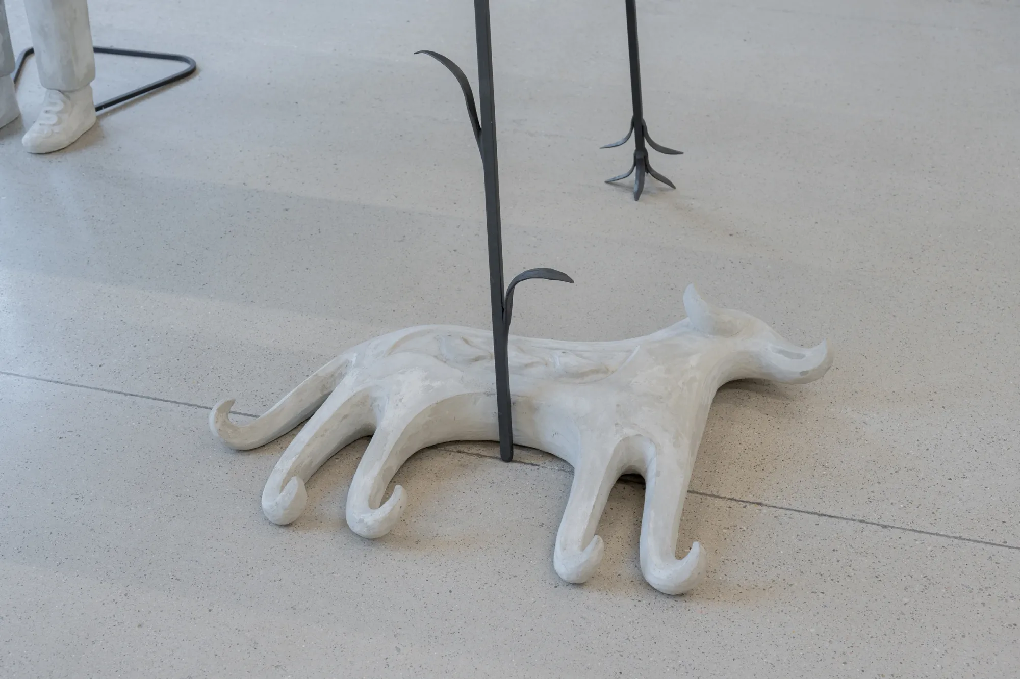 Exhibition review of Anna Hulačová: Signal V at Telegraph Gallery, Olomouc, 2026. Close-up detail of a pale plaster animal form with curled paws beneath a glass table.