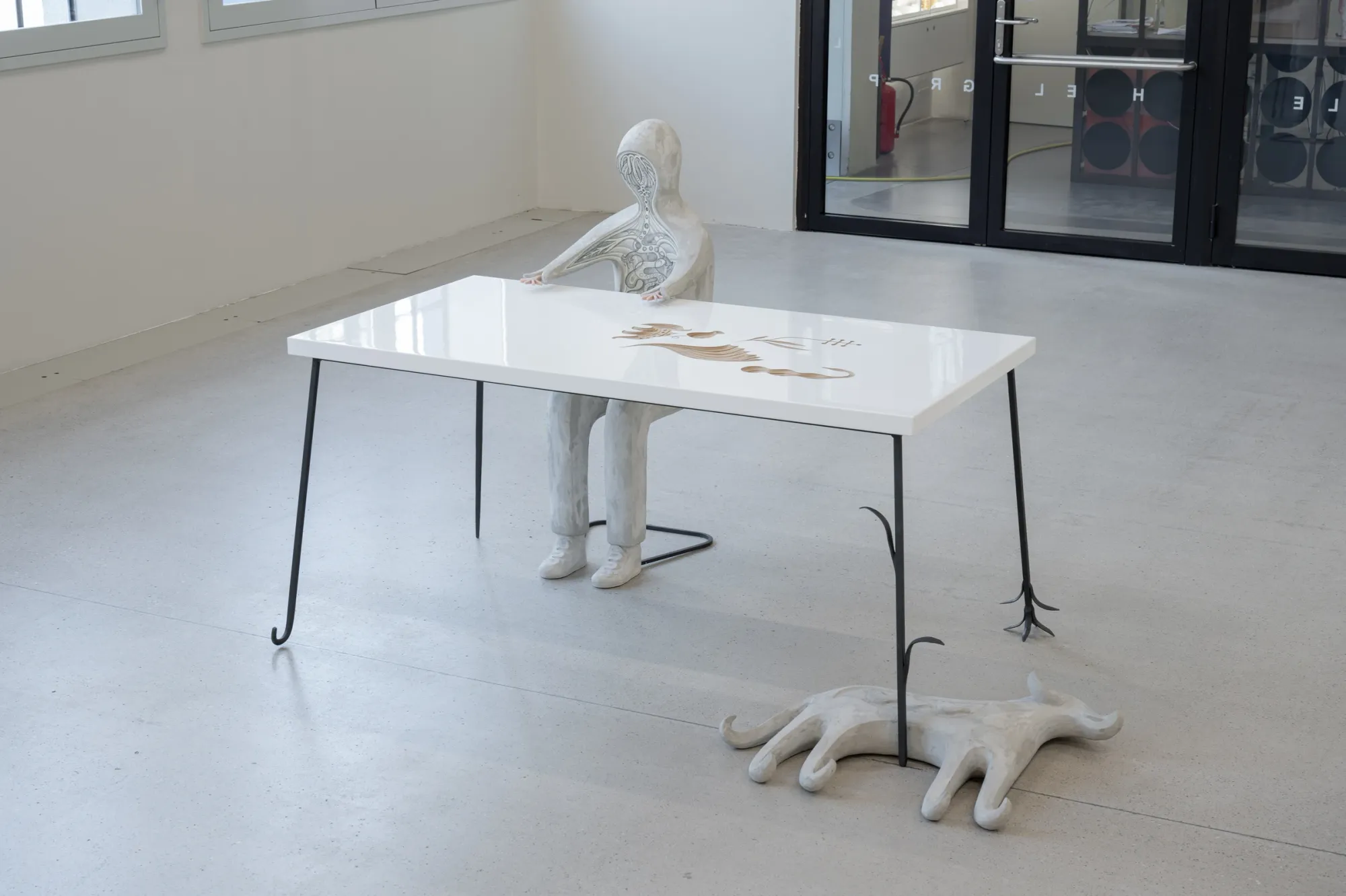 Exhibition review of Anna Hulačová: Signal V at Telegraph Gallery, Olomouc, 2026. Glass-topped table with a pale plaster figure and an animal form on the floor.