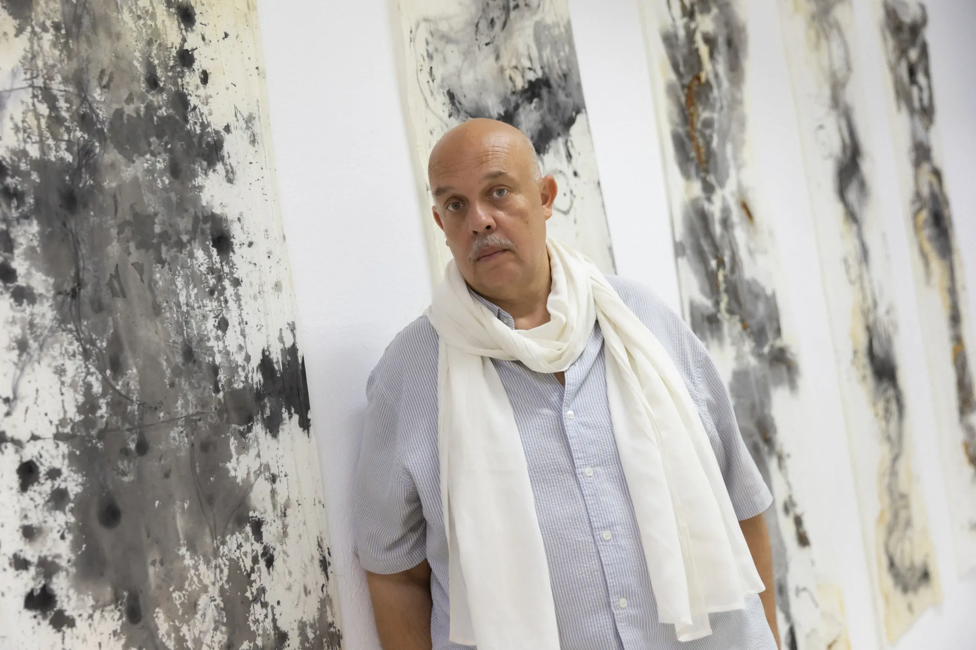 Exhibition review of Dimitrios Antonitsis, portrait of the curator and artist beside his black ink Shrouds paintings, Hydra, 2026..