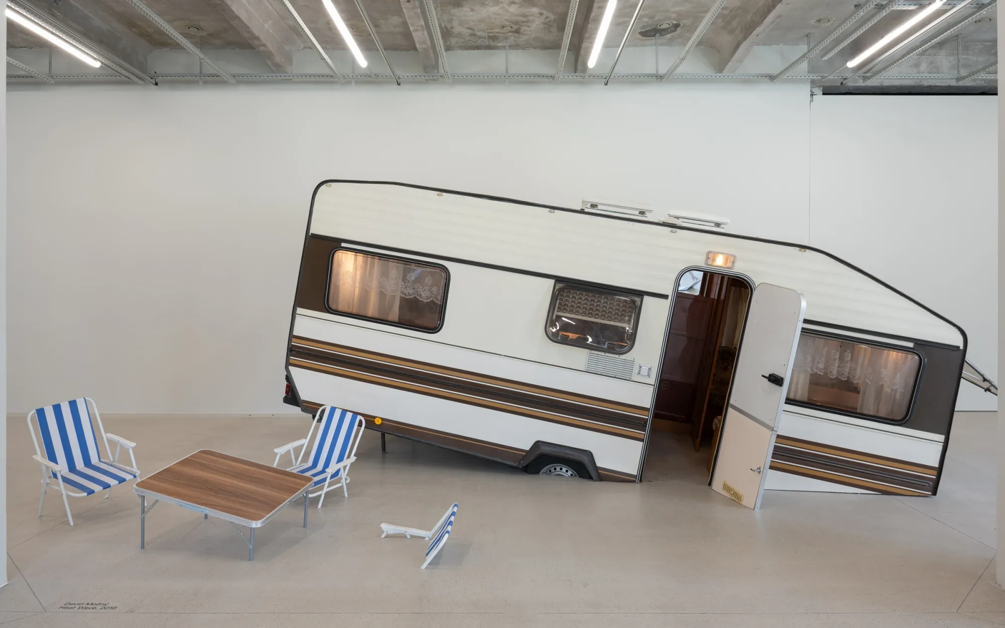 Exhibition review of David Možný: Signal V at Telegraph Gallery, Olomouc, 2026. Vintage caravan tilted as if sinking into the gallery floor.