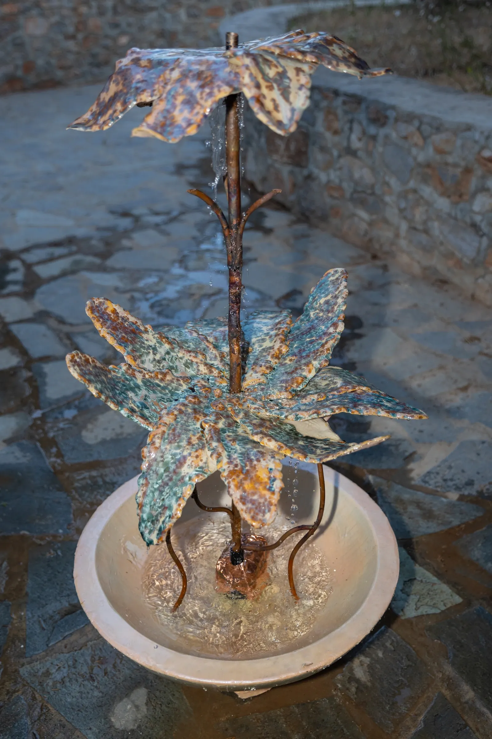 Exhibition review of Despina Charitonidi, a leaf shaped ceramic and metal fountain with running water in a terracotta basin, Hydra, 2026.