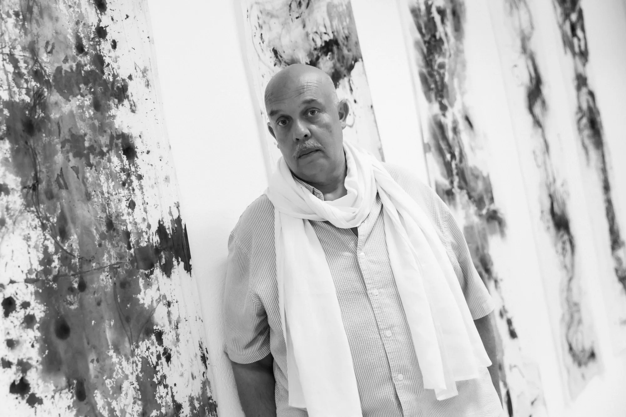Exhibition review of Dimitrios Antonitsis, portrait of the curator and artist beside his black ink Shrouds paintings, Hydra, 2026..