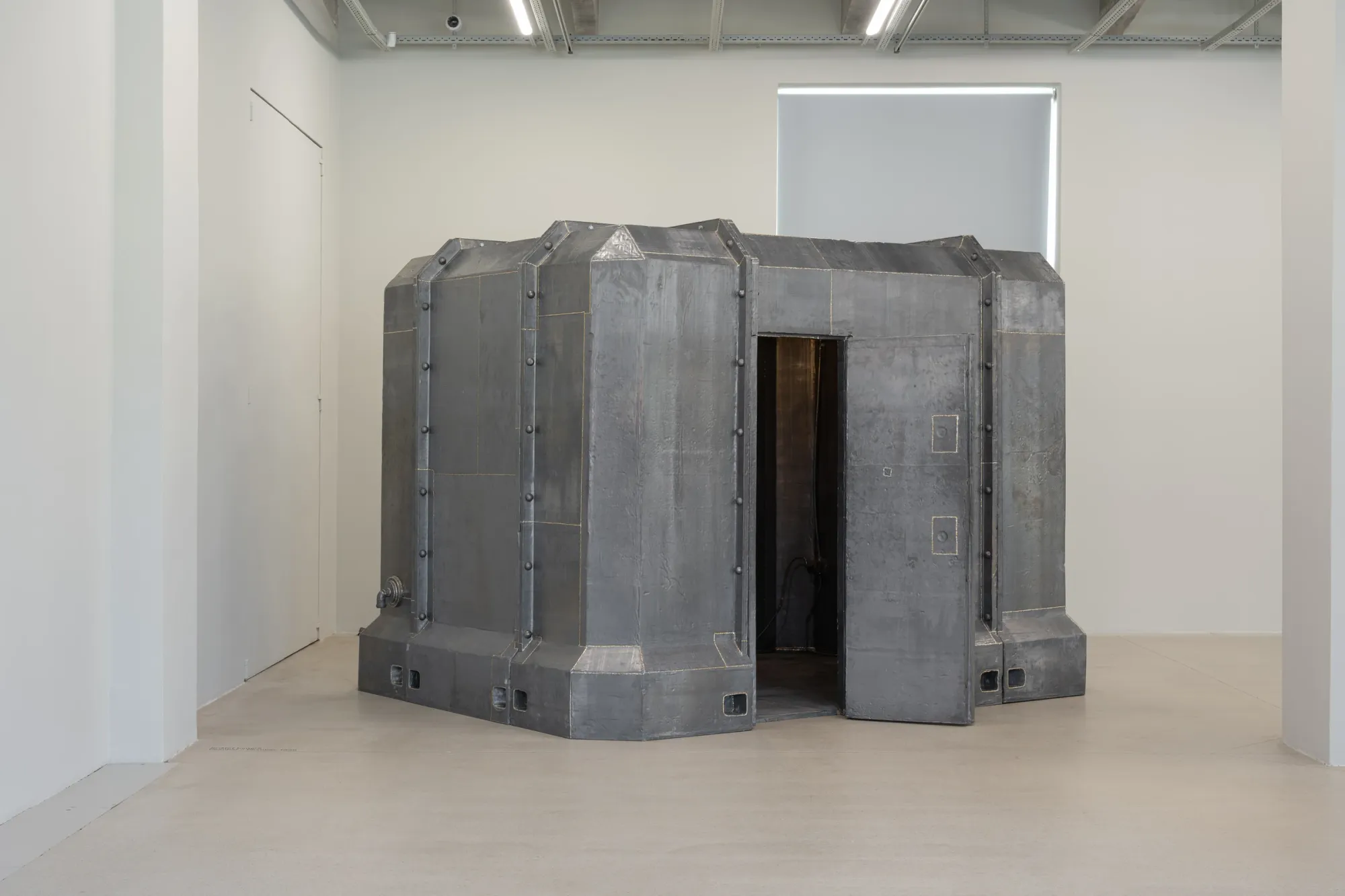 Exhibition review of Krištof Kintera: Signal V at Telegraph Gallery, Olomouc, 2026. Riveted grey steel vault with a heavy door standing open.