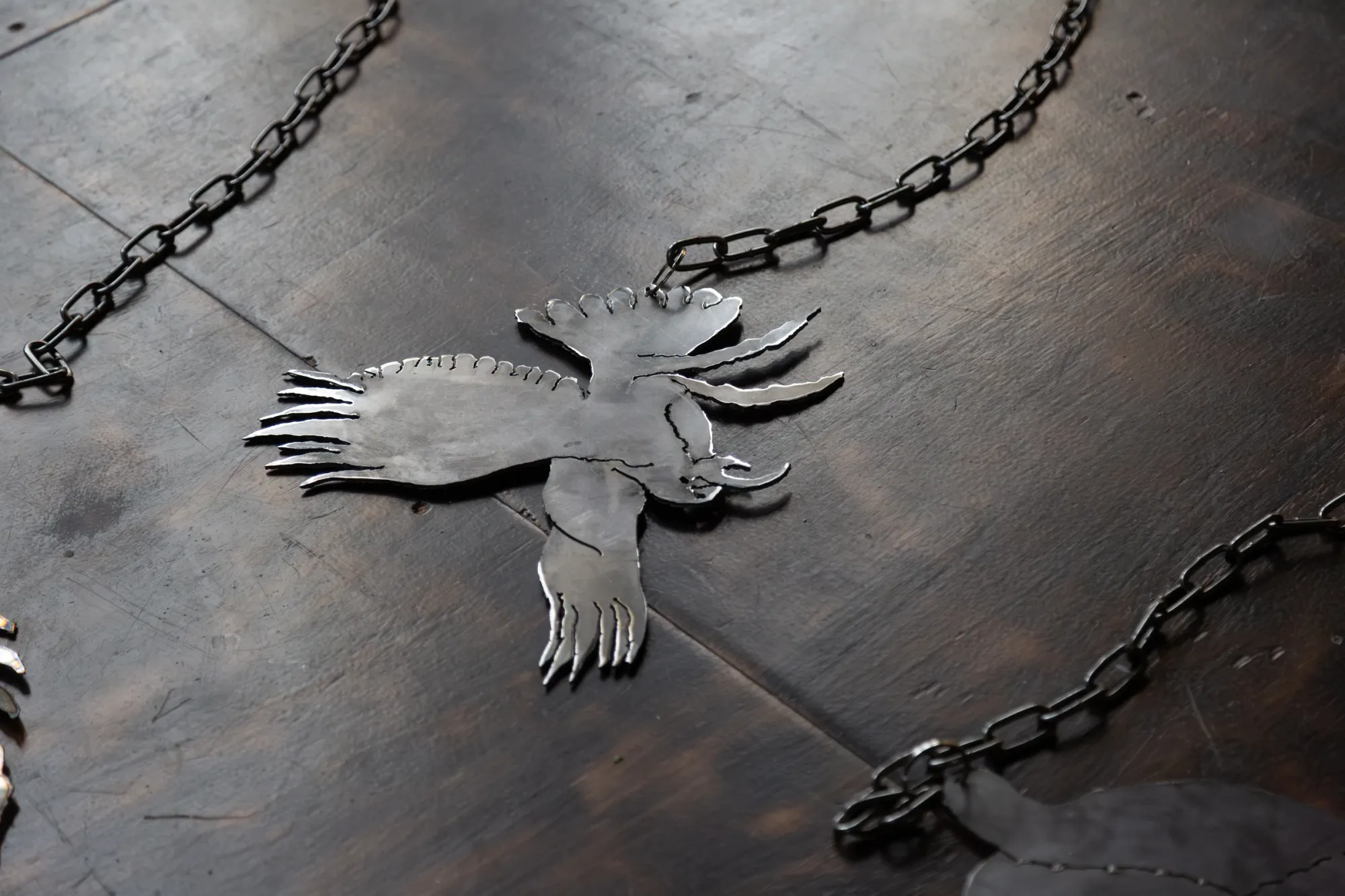  Nicola Genovese, Infinite Stage, detail, laser cut metal wing form resting among chains, Raleigh Chapel London, 2026