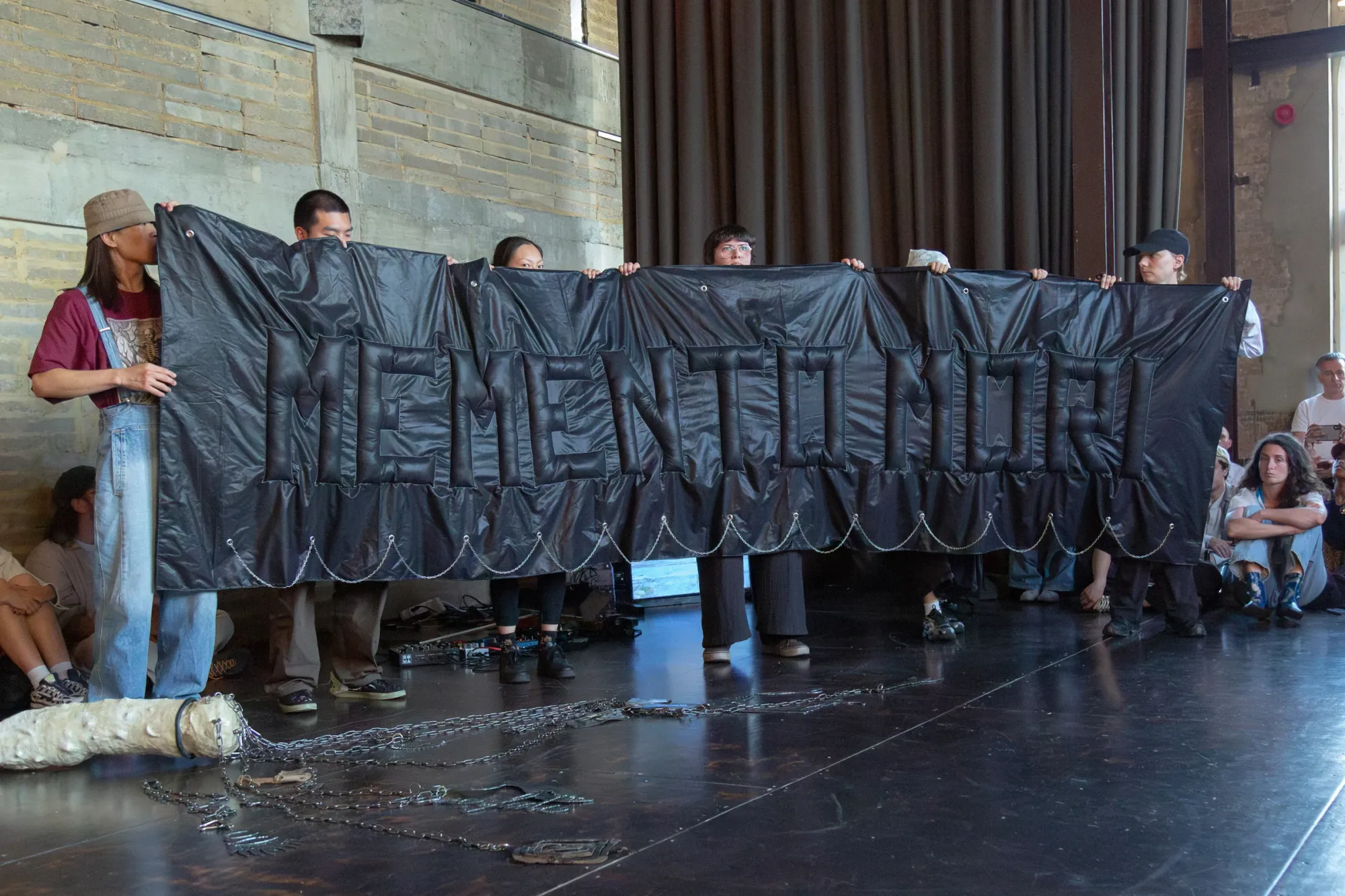 Nicola Genovese, Infinite Stage, Raleigh Chapel, London, 2026, six performers holding a padded black banner reading Memento Mori