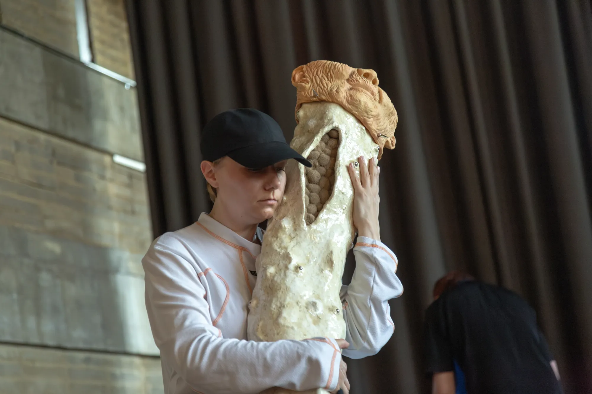 Nicola Genovese, Infinite Stage, Raleigh Chapel, London, 2026, performer holding a cast sculpture with an aged mask close to her face