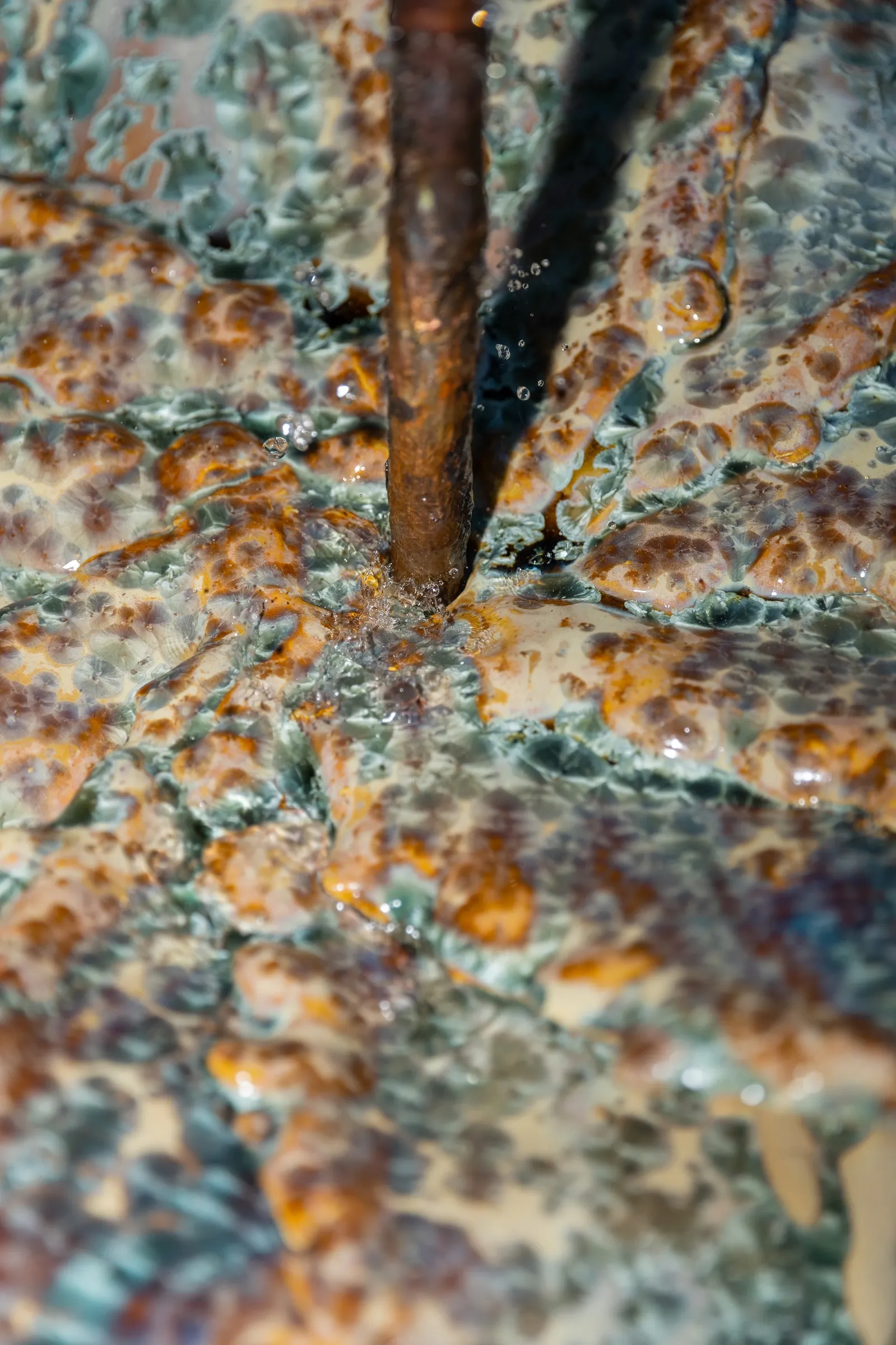 Exhibition review of Styliane Philippou: a visitor reclines on a green marble sculpture set in a shallow black reflecting pool, Hydra, 2026.