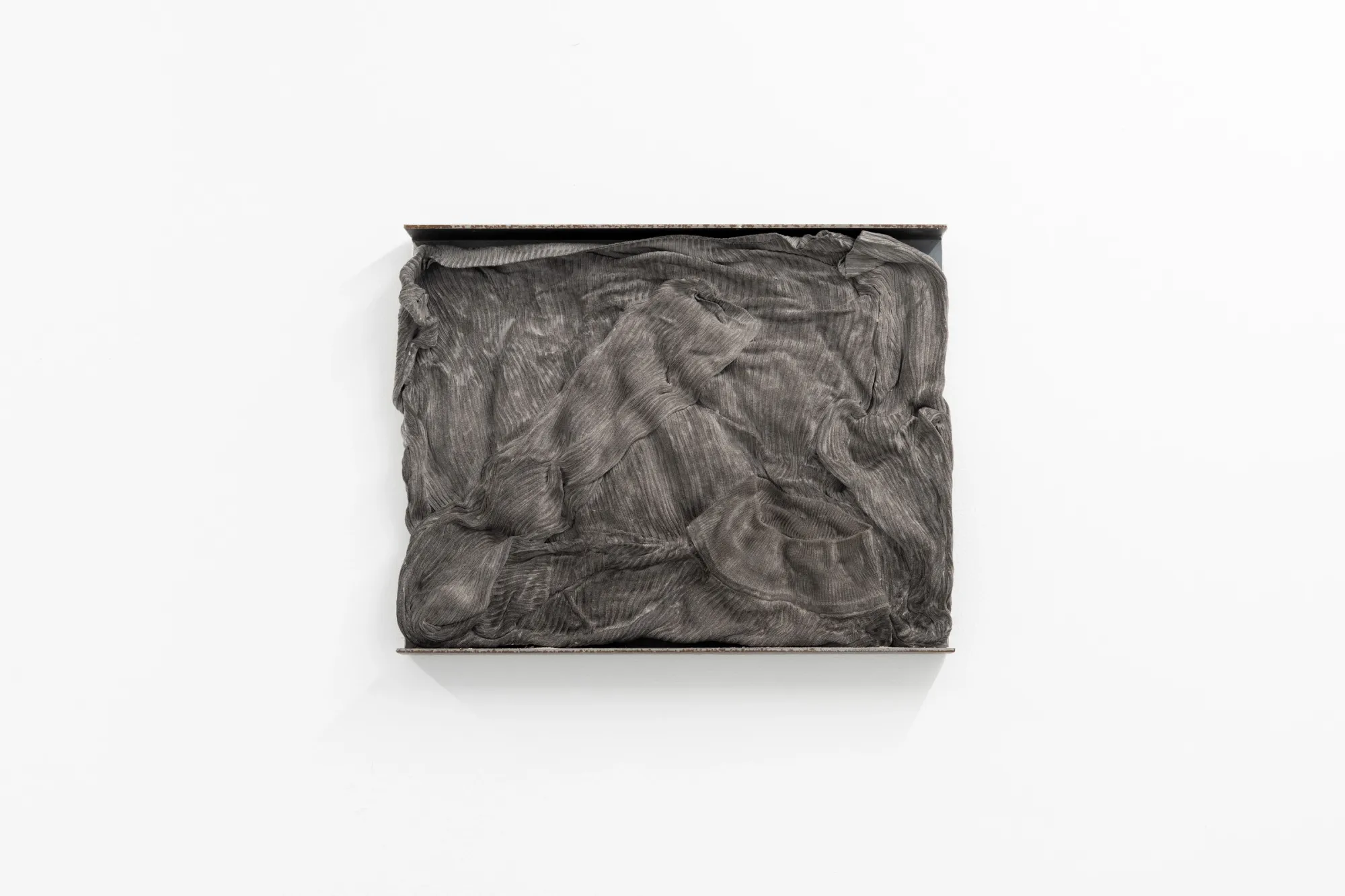 Exhibition review of Agnieszka Topolska: Call It Fate, Call It Karma at Galeria Skala, Poznań, 2026. Close-up of a grey fabric-textured cast relief panel with rippled folds.