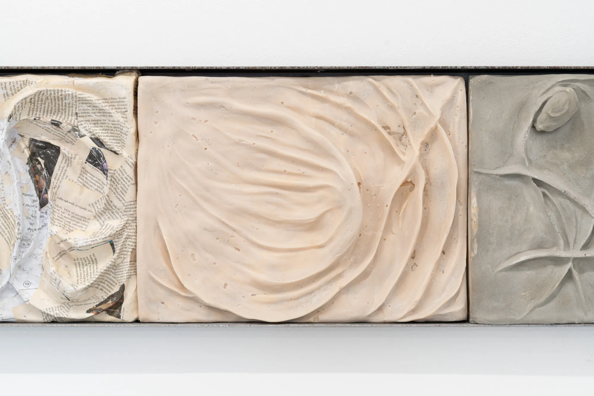 Exhibition review of Agnieszka Topolska: Call It Fate, Call It Karma at Galeria Skala, Poznań, 2026. Close-up of a relief tile with dried plant roots embedded in swirling grey plaster.