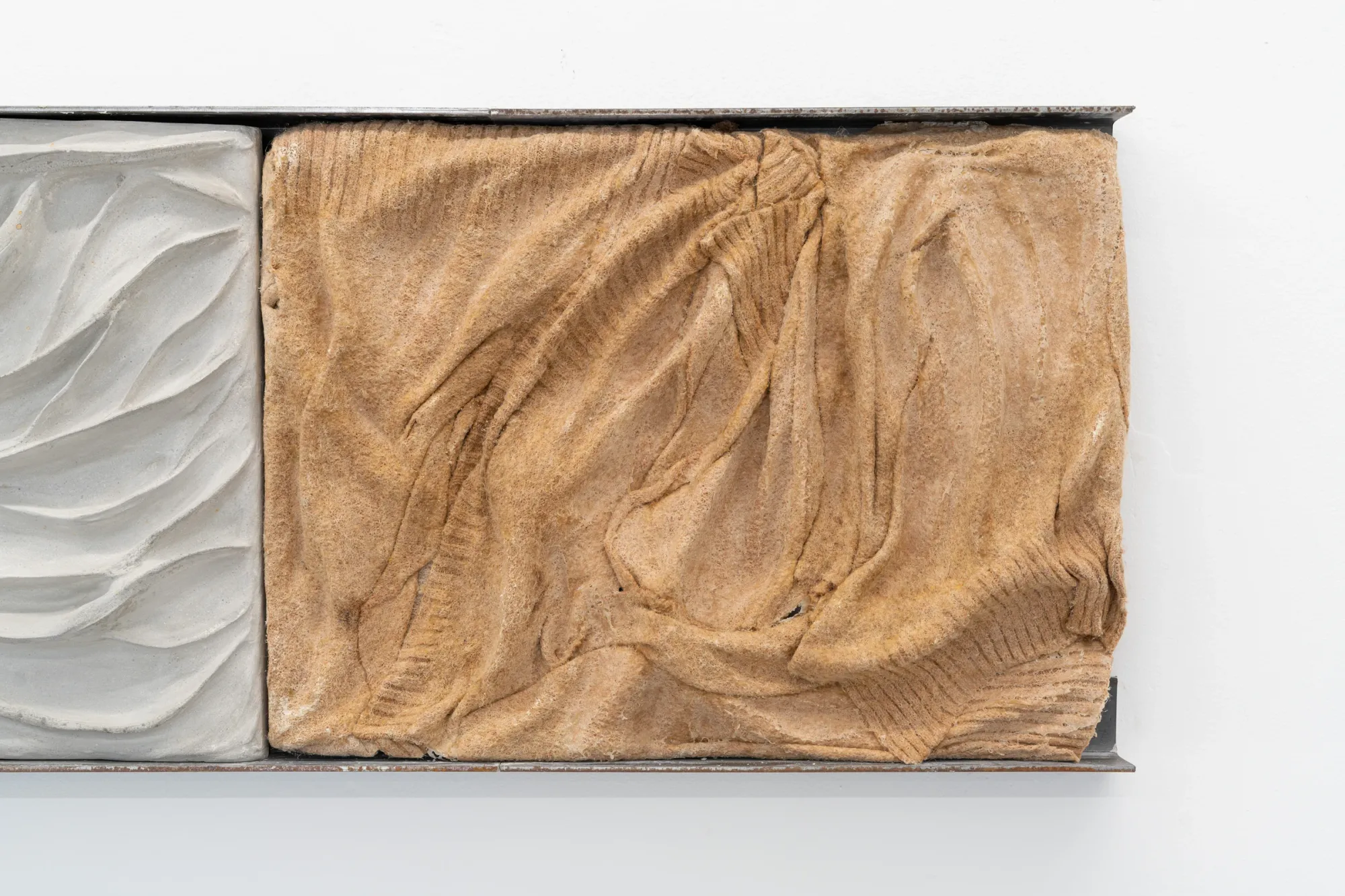 Exhibition review of Agnieszka Topolska: Call It Fate, Call It Karma at Galeria Skala, Poznań, 2026. Close-up of a tan corduroy-textured relief tile with deep folds.