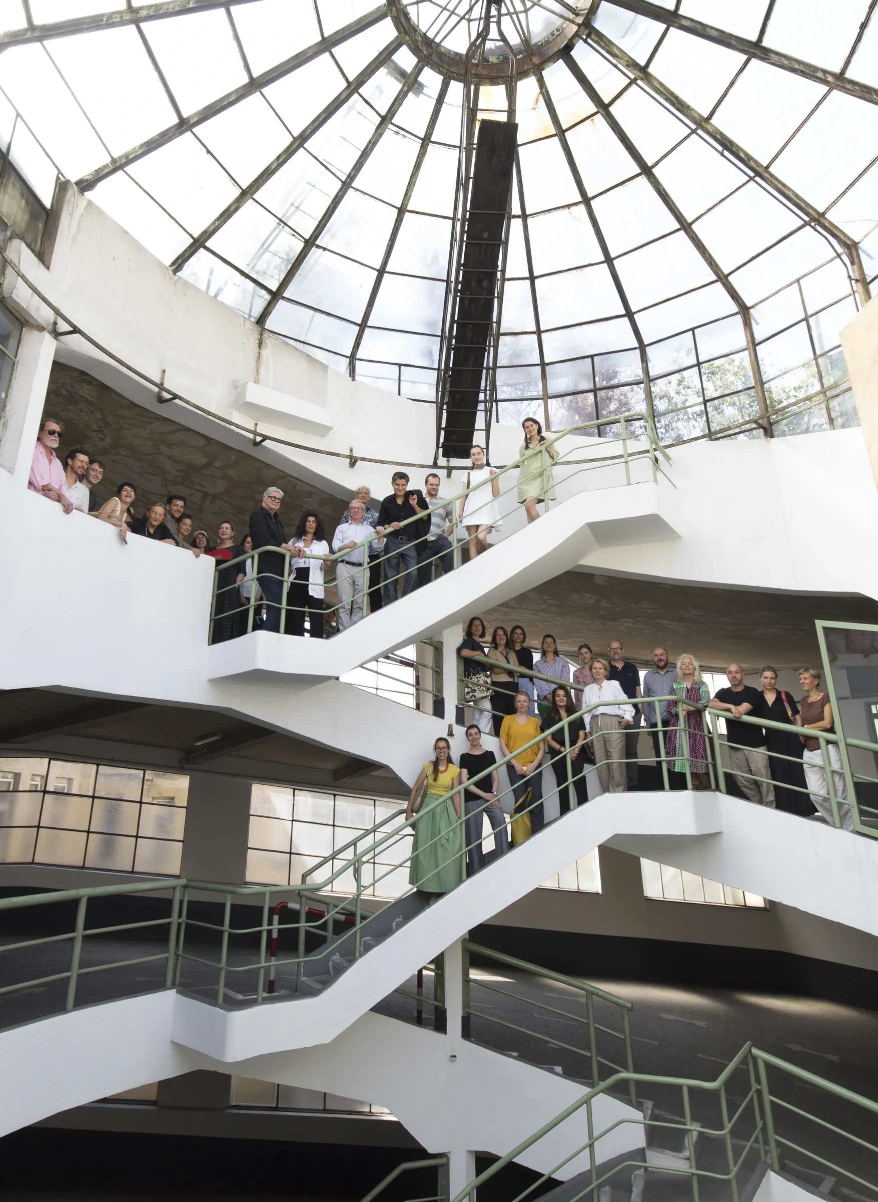 Astoria Artshow 2026: group portrait of Vienna gallerists gathered on the spiral staircase beneath Astoria Garage's glass dome.