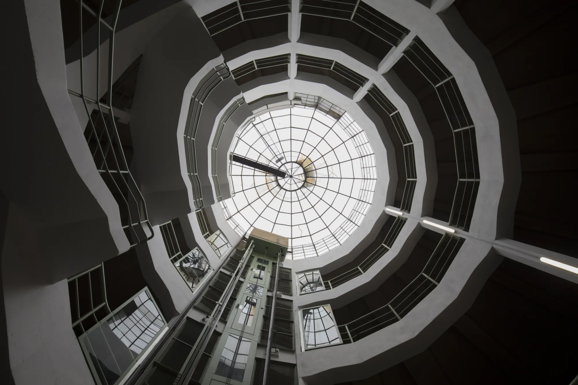 Astoria Artshow 2026: fisheye view looking straight up through the spiral stairwell to the glass dome ceiling of Astoria Garage, Vienna.