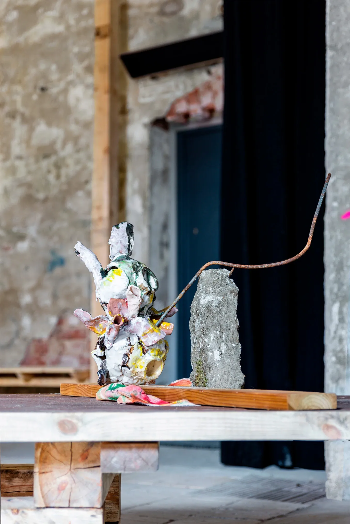 Exhibition review of Dan Kim: White Nights at AaltoSiilo, Oulu, 2026. A glazed ceramic figure arched by rusted rebar beside a stone pillar.