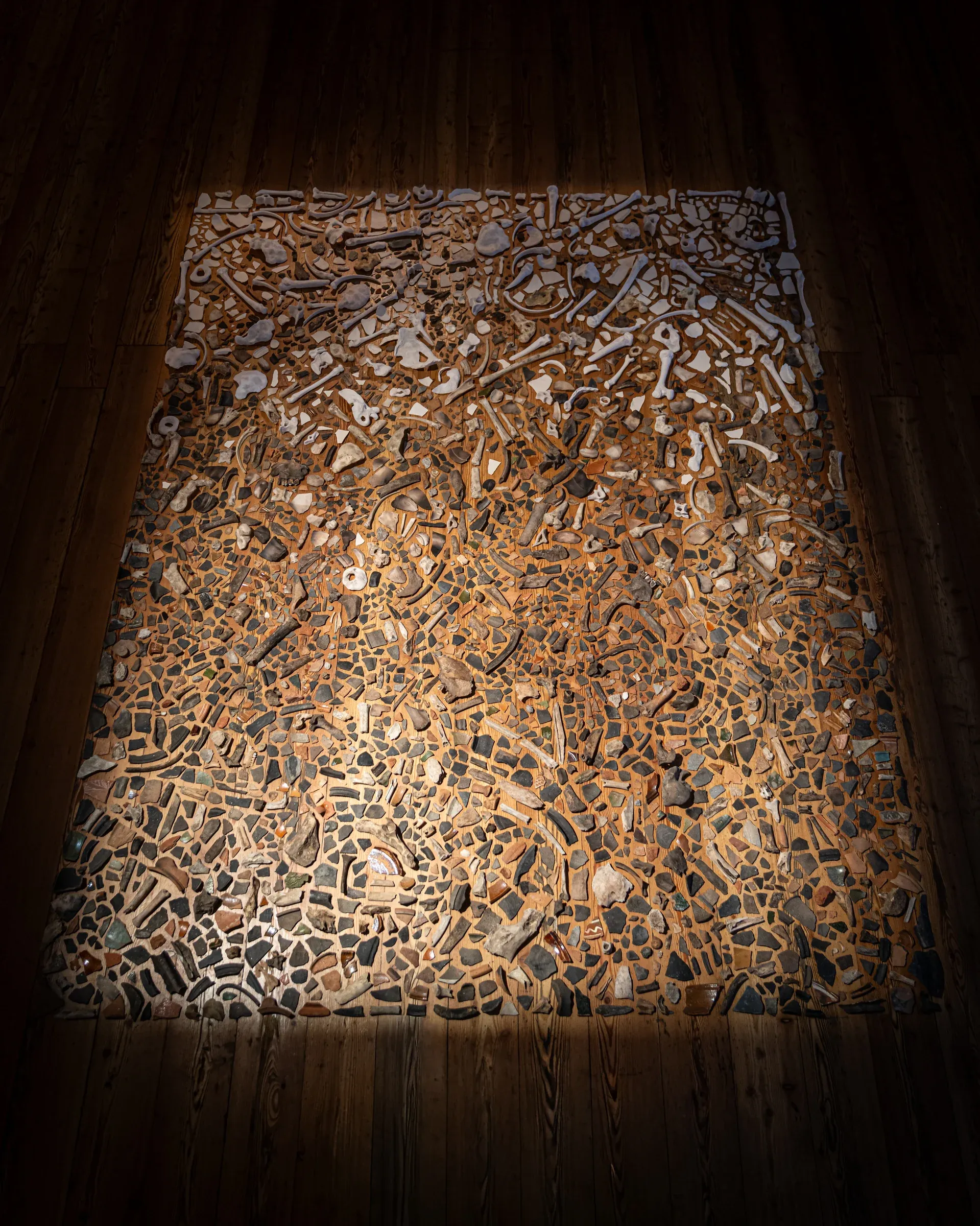 Exhibition review of Daniel Wetzelberger: TRANSFER at Kulturforum Laßnitzhaus, Deutschlandsberg, 2026. Close-up of unglazed ceramic fragments and bone pieces sorted on the floor.