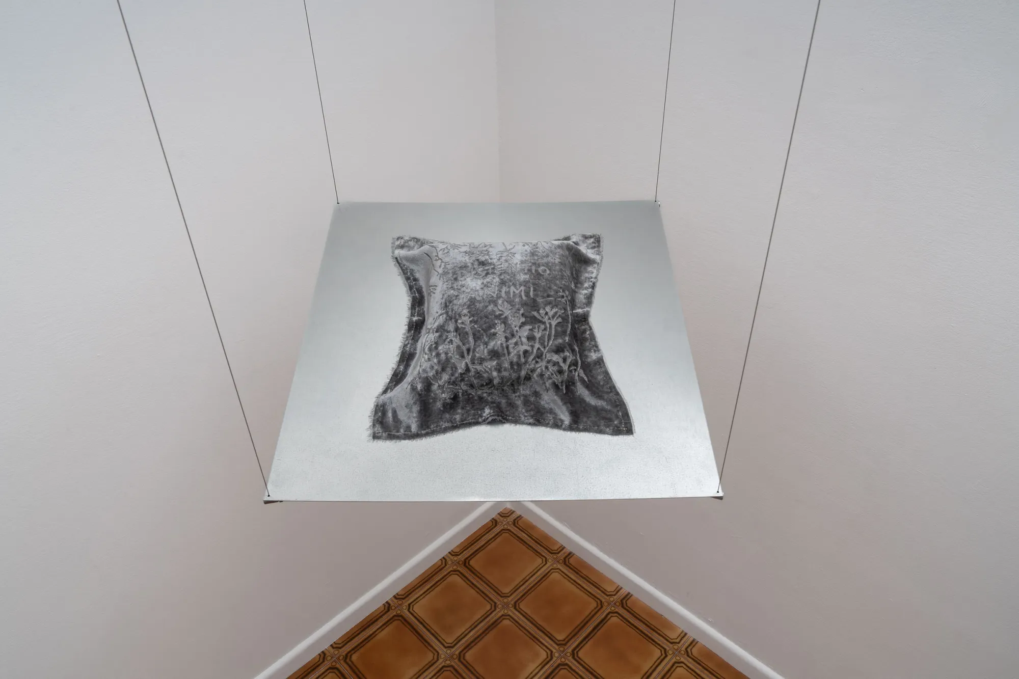 catapult contemporary art platform review Exhibition review of Elena Adamou: Iconographies at primopiano, Montesilvano, 2026. Red-lit room with a brick planter of wildflowers beneath a glowing bulb and shuttered window.