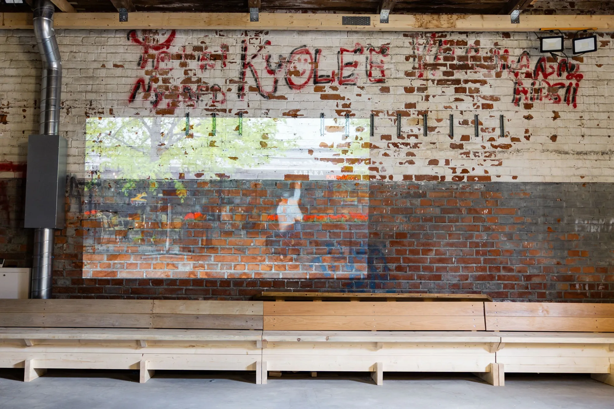 Exhibition review of Jin Hong: White Nights at AaltoSiilo, Oulu, 2026. Video projection glowing faintly on a brick wall marked with graffiti.