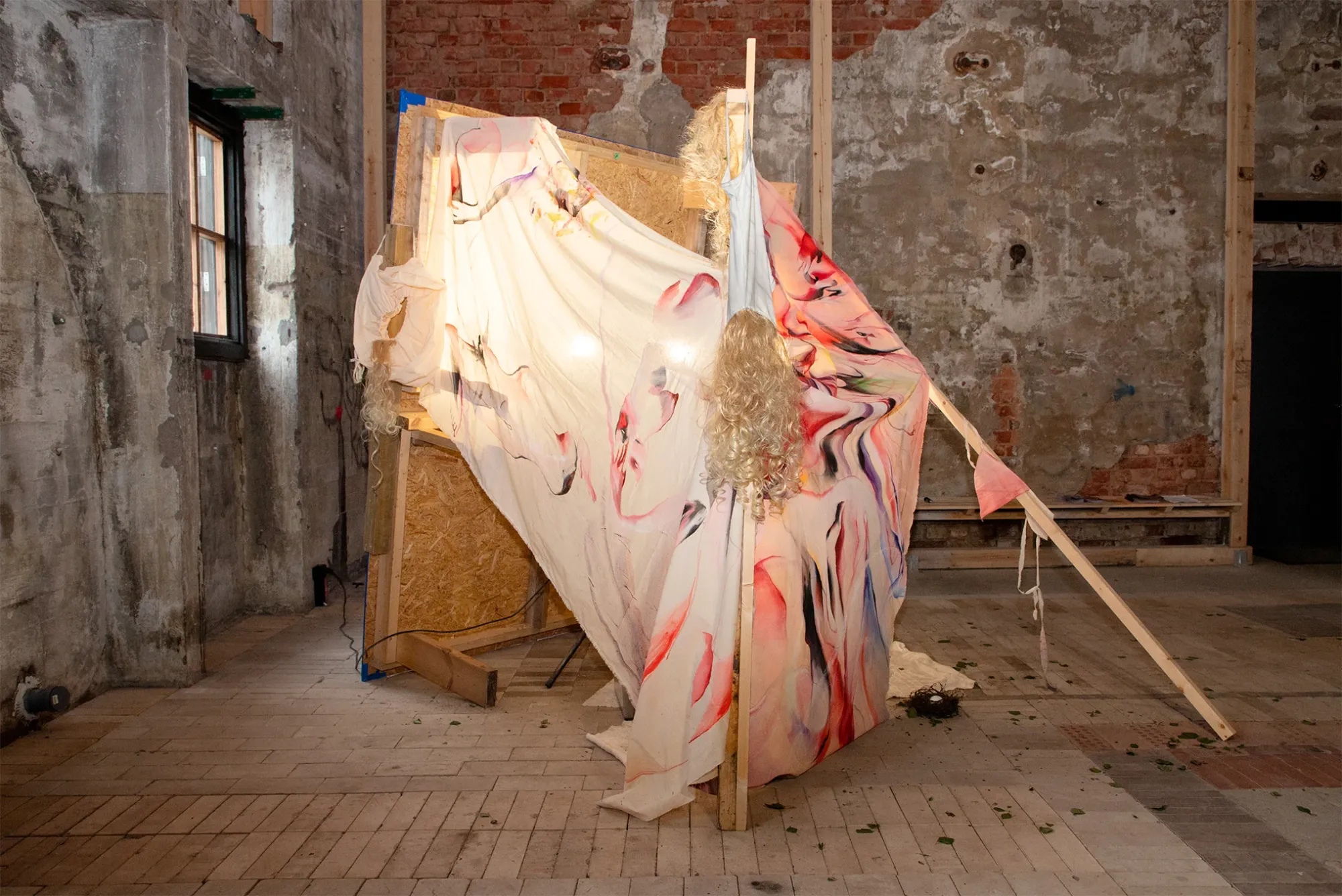 Exhibition review of Juae Park: White Nights at AaltoSiilo, Oulu, 2026. A painted fabric shelter lit from within, blonde wig hanging at its frame.