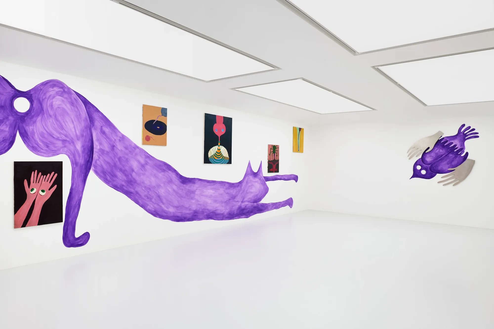 Exhibition review of Kallirroi Ioannidou: Galvanizing Memories at Kallmann-Museum, Ismaning, 2026. Wide gallery view with a purple cat mural on one wall and a purple bird mural with metal wings on the opposite wall.