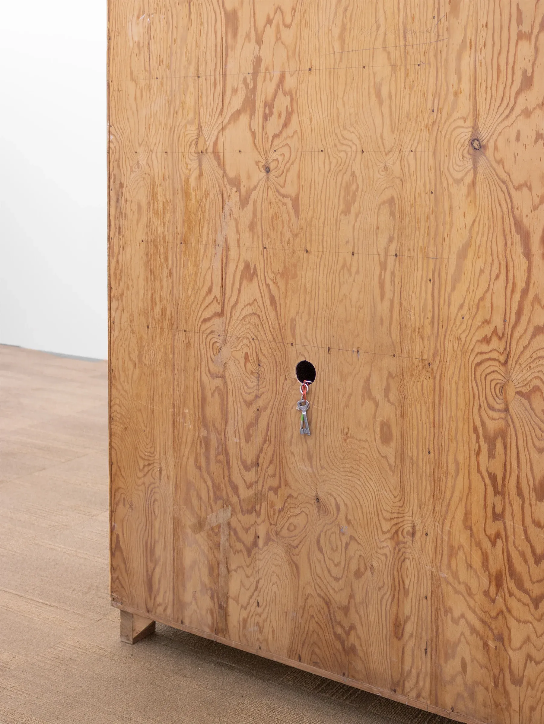 Exhibition review of Jana Köhle and Dominik Münch: Kabinett at Emergency Space, Paris, 2026. Close-up of a wood grain cabinet door with a key ring hanging from a small round opening. catapult contemporary
