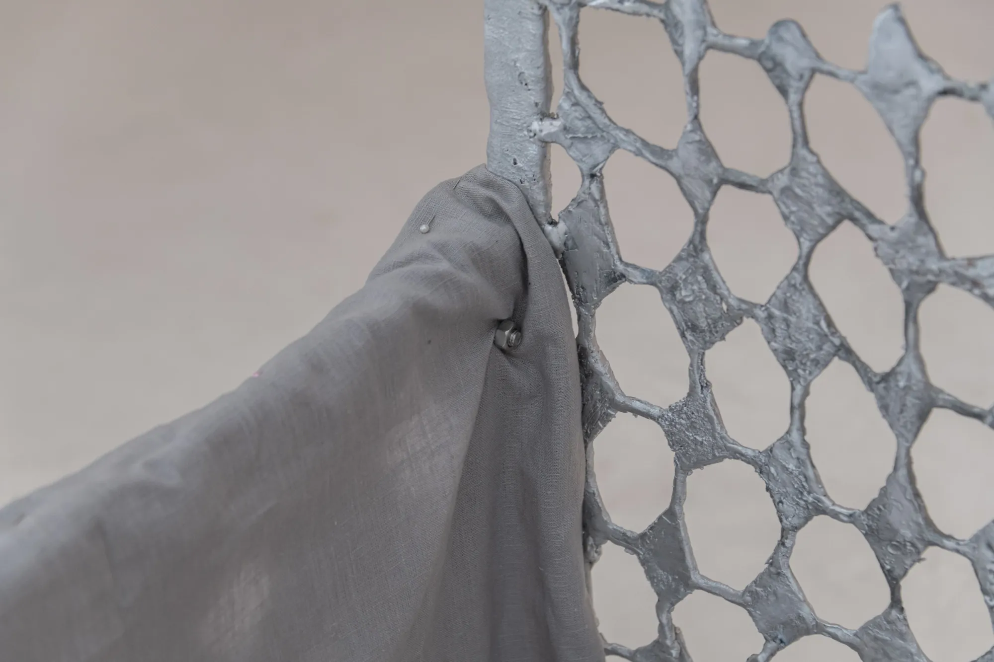 Exhibition review of Maija Fox: As the sap rises at OUTPOST, Norwich, 2026. A grey linen cloth draped over the edge of a cast diamond-mesh screen.