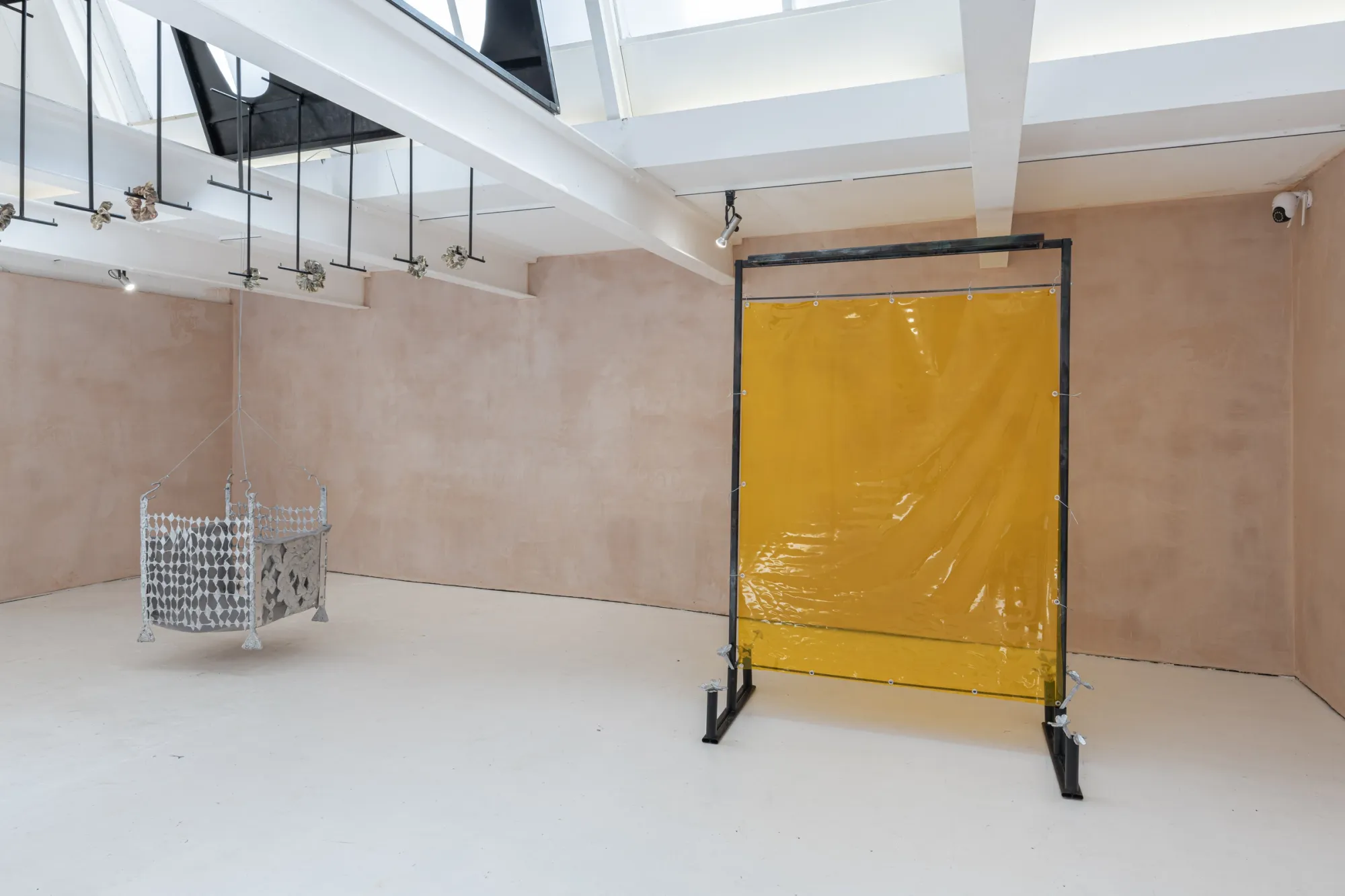 Exhibition review of Maija Fox: As the sap rises at OUTPOST, Norwich, 2026. A hanging mesh screen and yellow curtain beneath white ceiling beams.