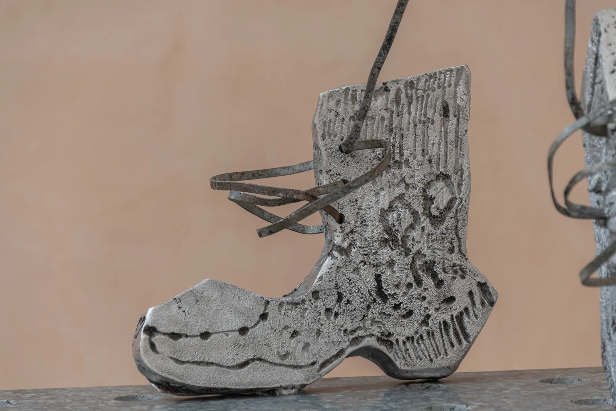 Exhibition review of Maija Fox: As the sap rises at OUTPOST, Norwich, 2026. A cast aluminium work boot with laces standing on a granite tabletop.