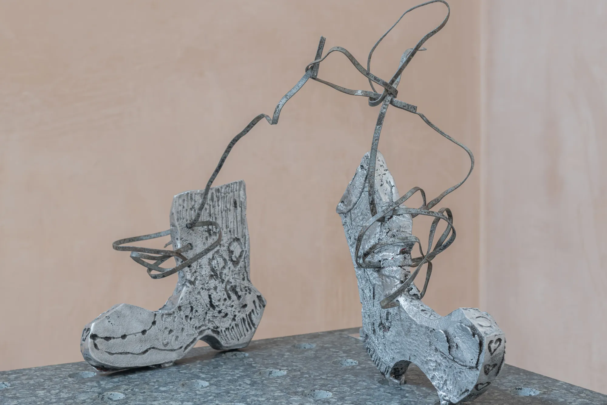 Exhibition review of Maija Fox: As the sap rises at OUTPOST, Norwich, 2026. Two cast aluminium boots with wire stems rising from them like plant growth.