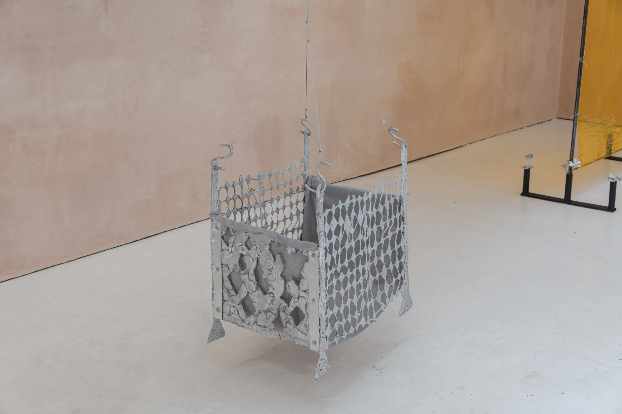Exhibition review of Maija Fox: As the sap rises at OUTPOST, Norwich, 2026. A cast aluminium diamond-mesh basket structure hanging on wire.