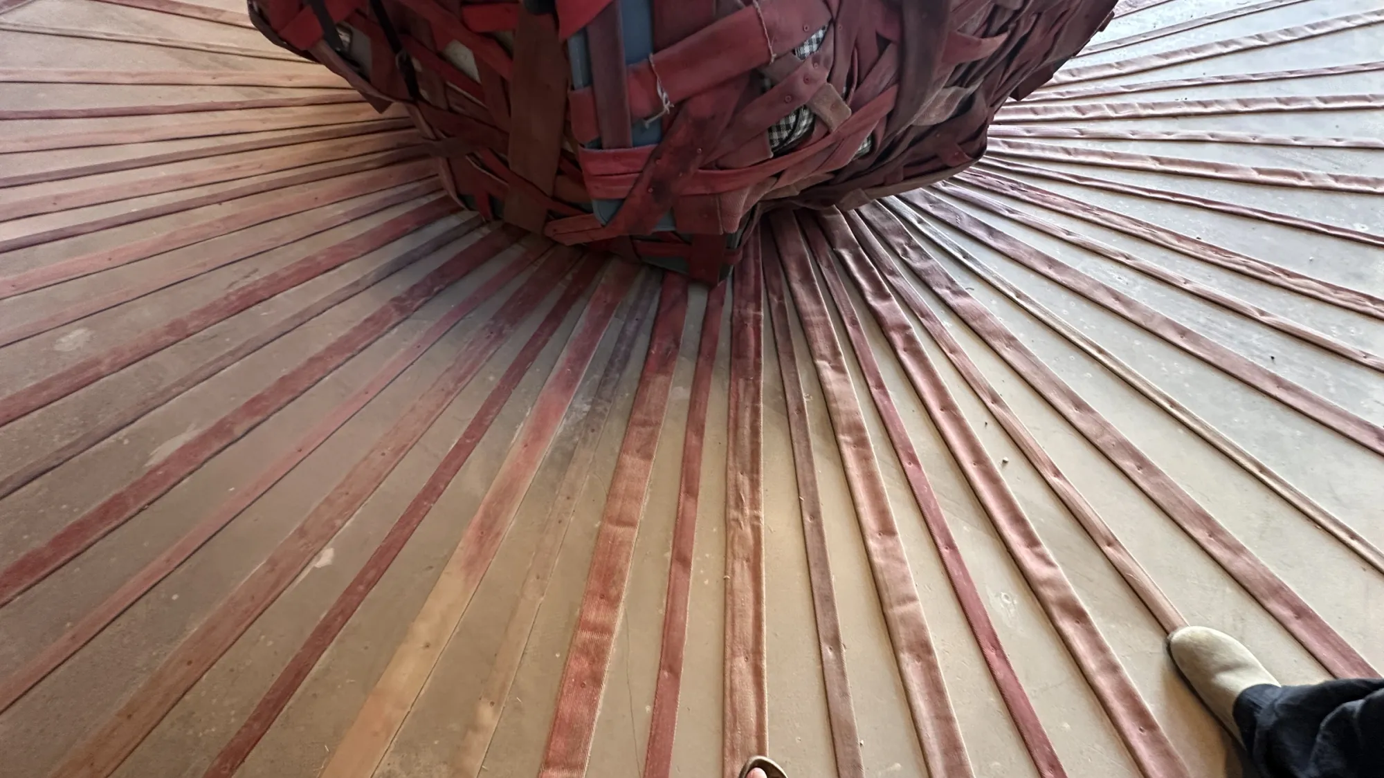Exhibition review of Nari Ward: Until That Day at DESTE Foundation, Slaughterhouse, Hydra, 2026. Three graduated red woven spheres lined up against a bare concrete wall.