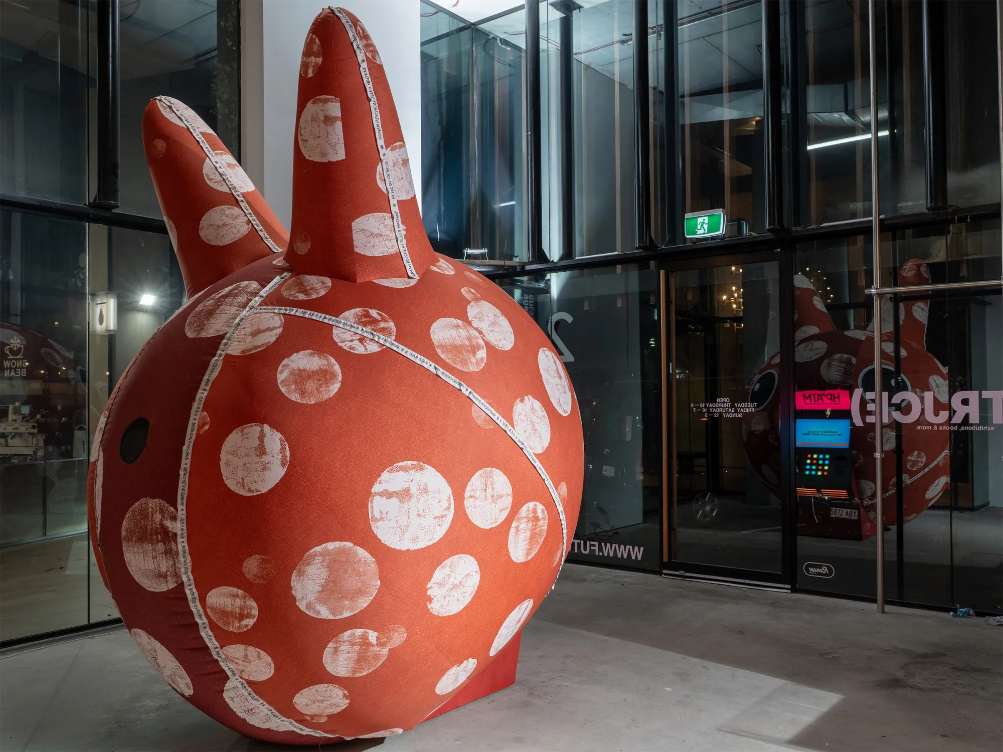 Exhibition review of Nimrod Weis: HPATM at FUTUREJUICE, Adelaide, 2026. Exterior night view, the machine glowing behind reflective glass.
