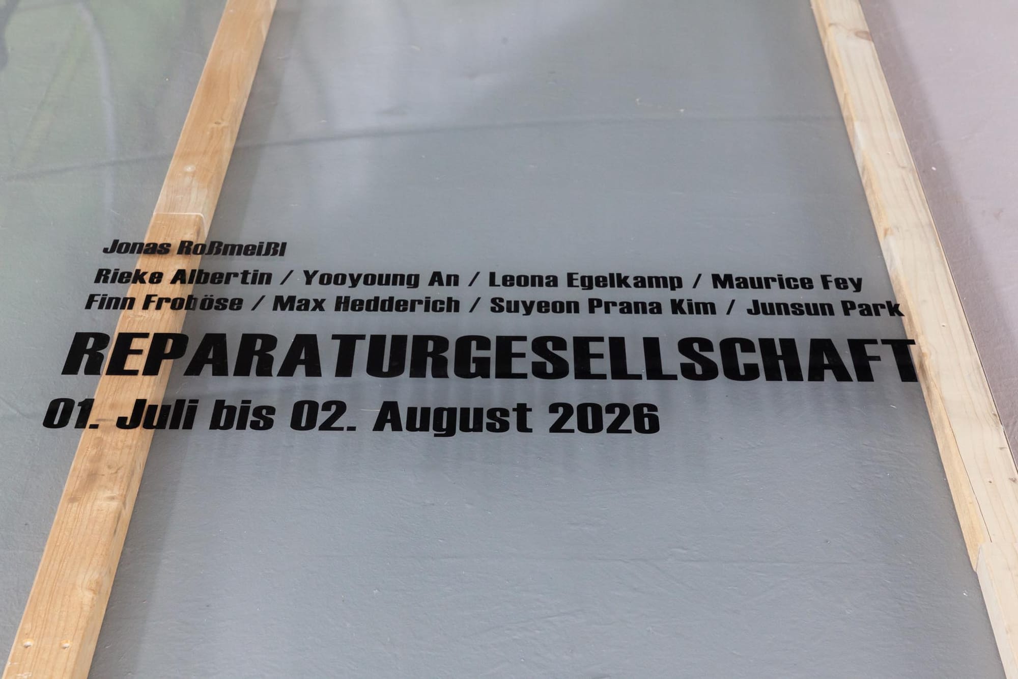 Reparaturgesellschaft, Wewerka Pavilion, Münster, 2026, detail of glass floor panel printed with exhibition title, dates, and artist names