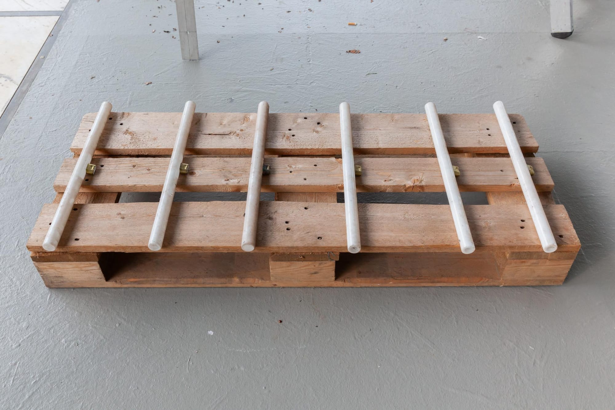 Reparaturgesellschaft, Wewerka Pavilion, Münster, 2026, wooden pallet with white marble rods threaded through slats and brass fittings