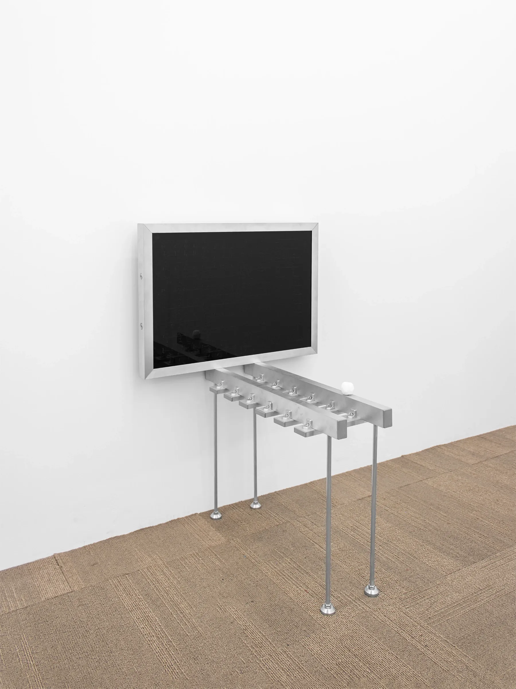 Exhibition review of Romain Sarrot: Concerto N°3 ascese alla luna 1/2 at Emergency Space, Paris, 2026. Black glossy Altuglass panel on an aluminum tube stand resembling a screen.