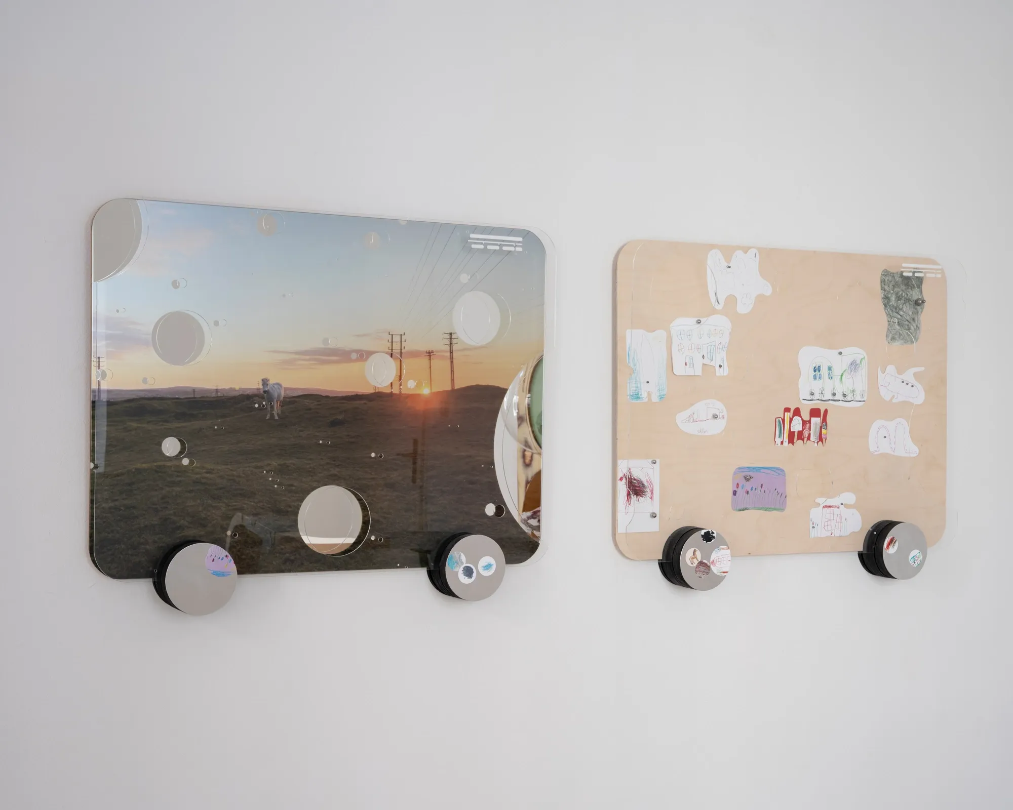 Exhibition review of Sebastian Scholz: ludo at global international, Vienna, 2026. Close-up of a waggon's plywood surface with a child's drawing sticker and an aluminium wheel.