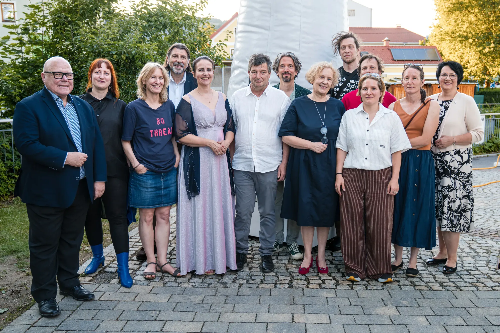 Exhibition review of TRANSFER at Kulturforum Laßnitzhaus, Deutschlandsberg, 2026. A group posed outdoors in front of the tall white inflatable statue.